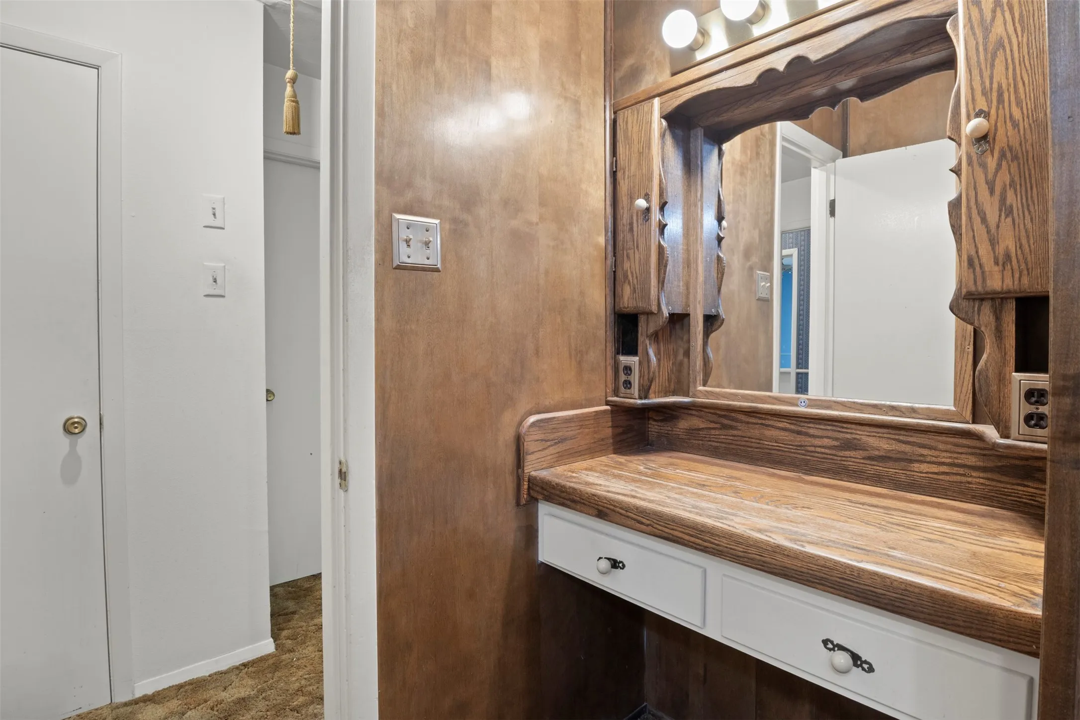 Built-in vanity with wood-finish countertop, integrated mirror, and dual vanity lights