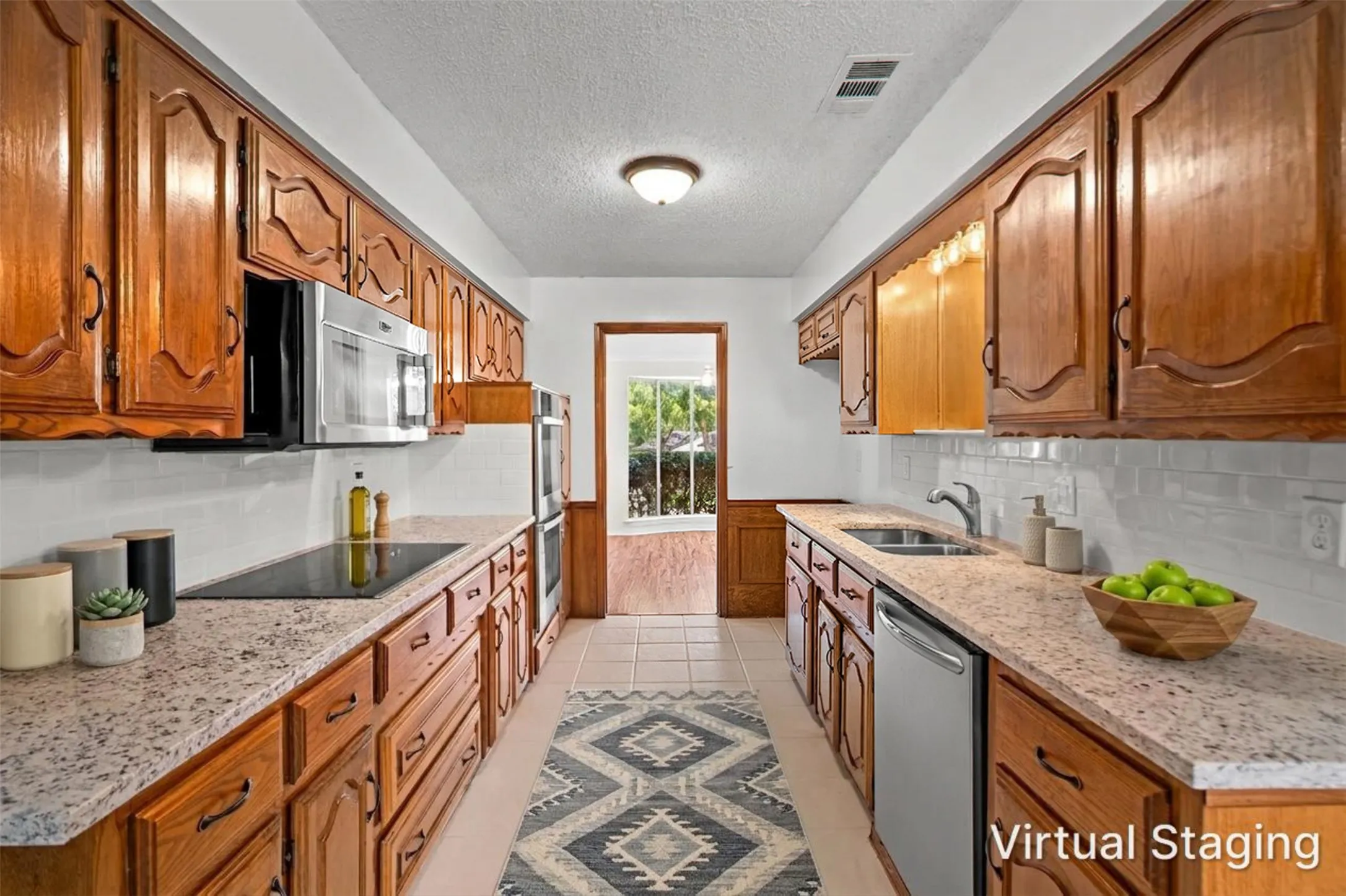 Galley kitchen featuring wood cabinetry, stone-finish countertops, stainless steel appliances, a tile backsplash, and recessed lighting
