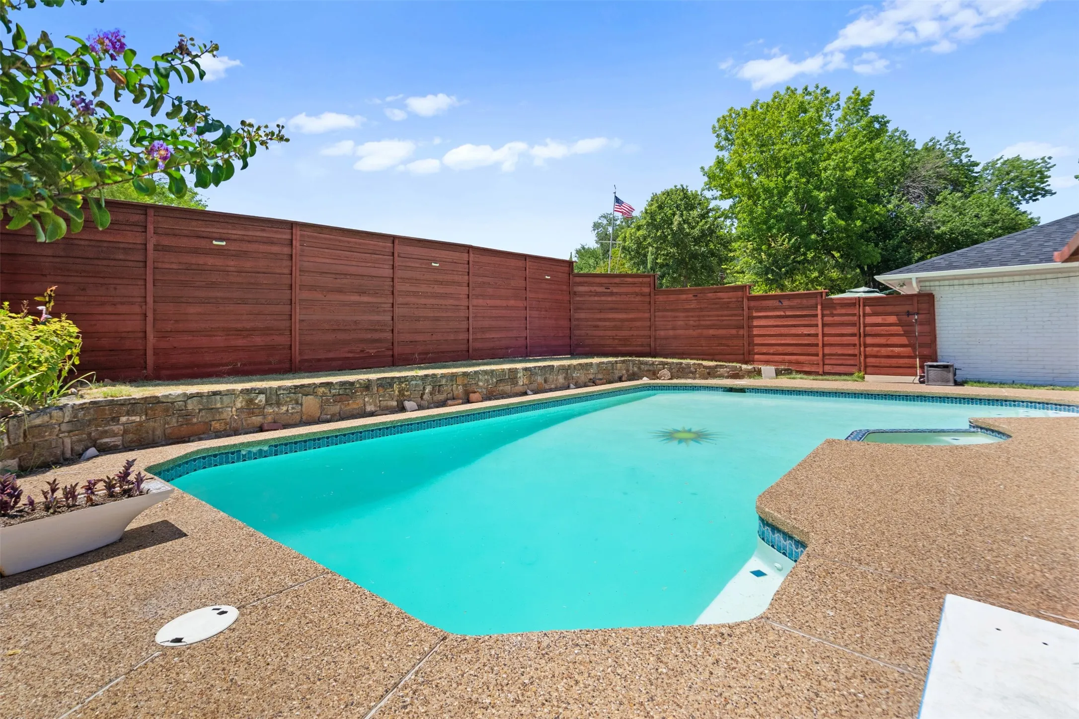 Outdoor swimming pool with integrated spa and surrounding aggregate decking