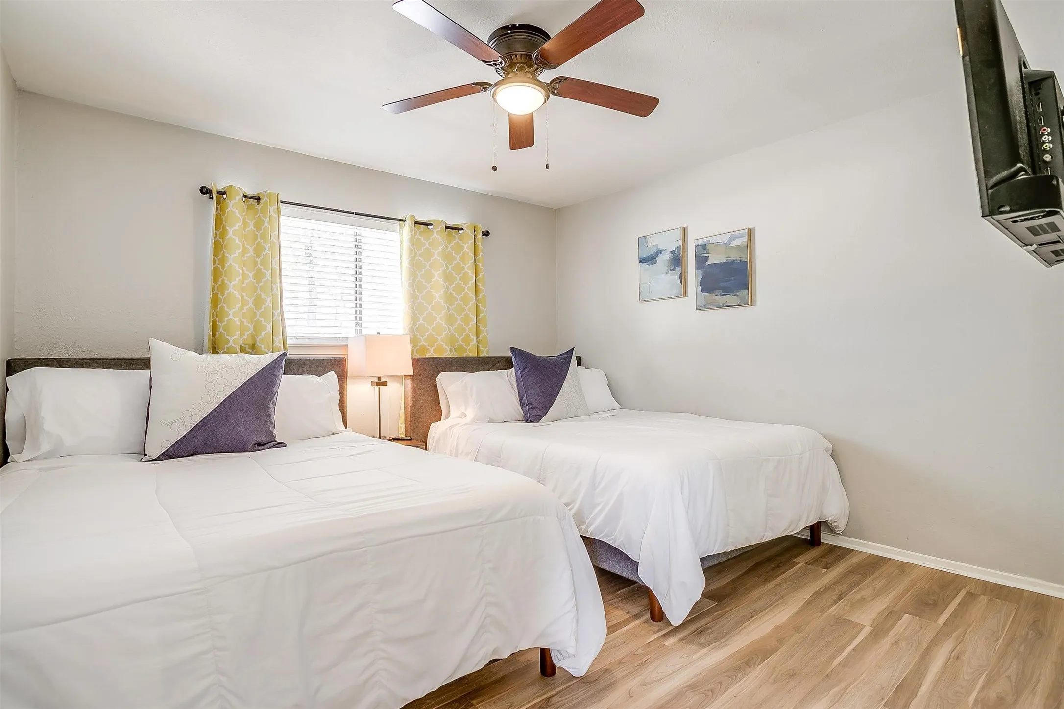 Room featuring wood-finish flooring, a ceiling fan with integrated lighting, and a window with blinds