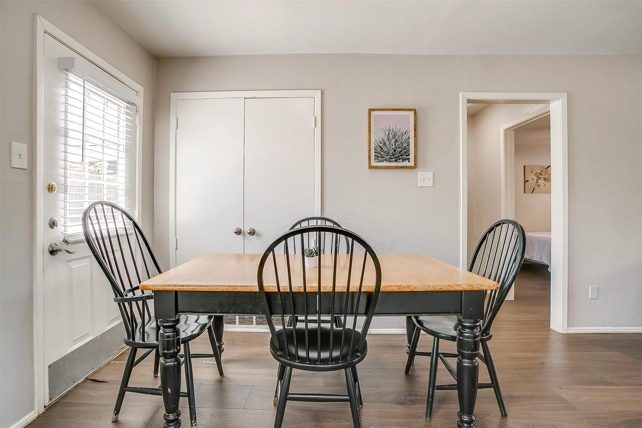 Interior space featuring wood-finish flooring, light gray wall paint, a white door with blinds, and white bi-fold closet doors