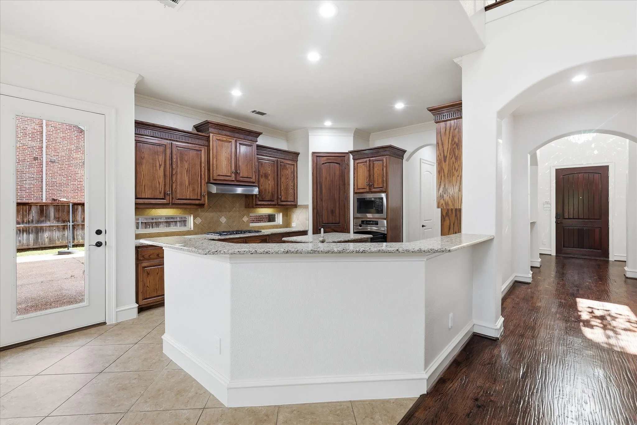 Kitchen featuring wood cabinetry, built-in stainless steel appliances, and a breakfast bar with a light-toned countertop