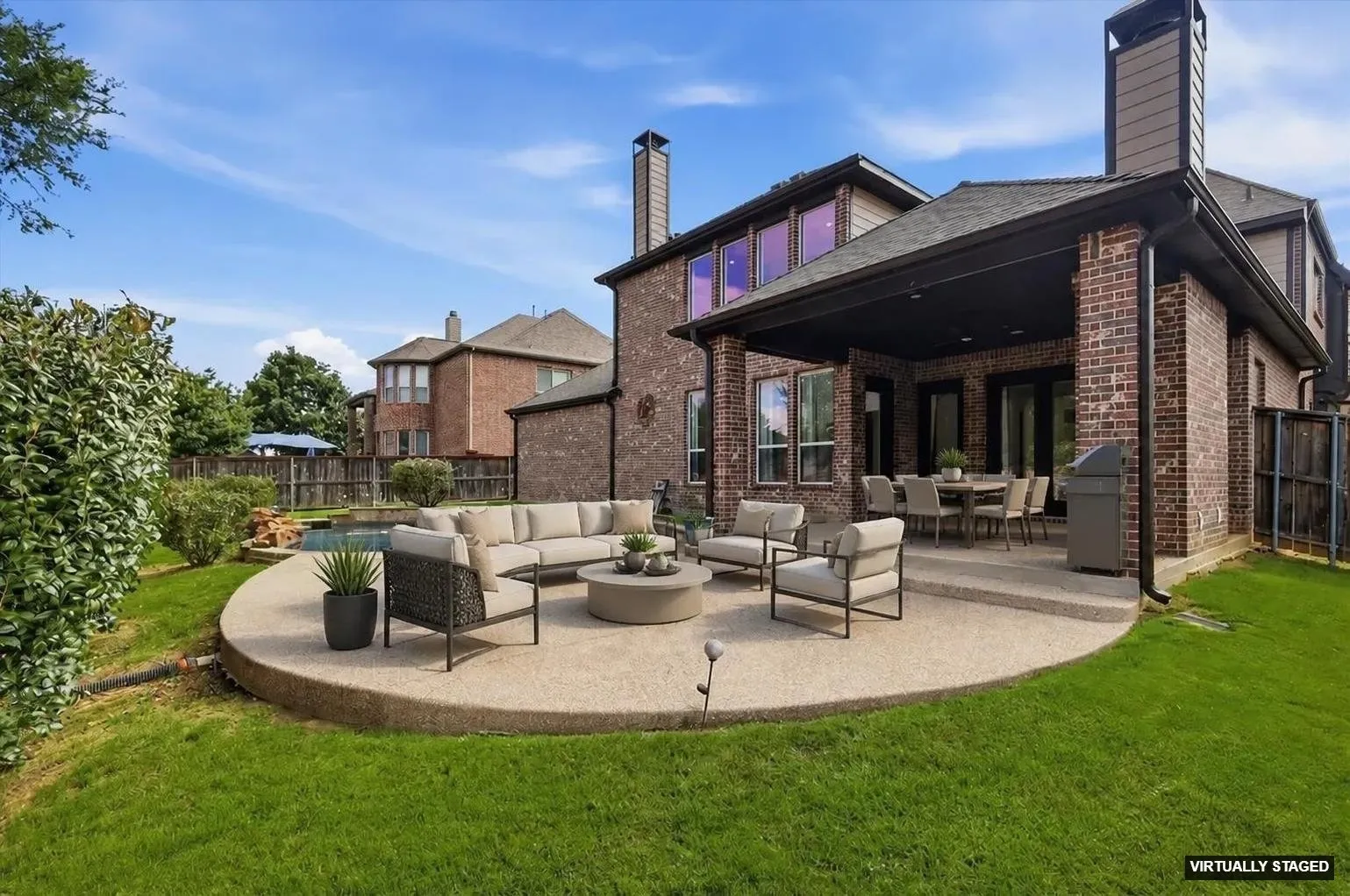 Spacious backyard featuring an extensive lawn, covered patio, and rounded concrete patio
