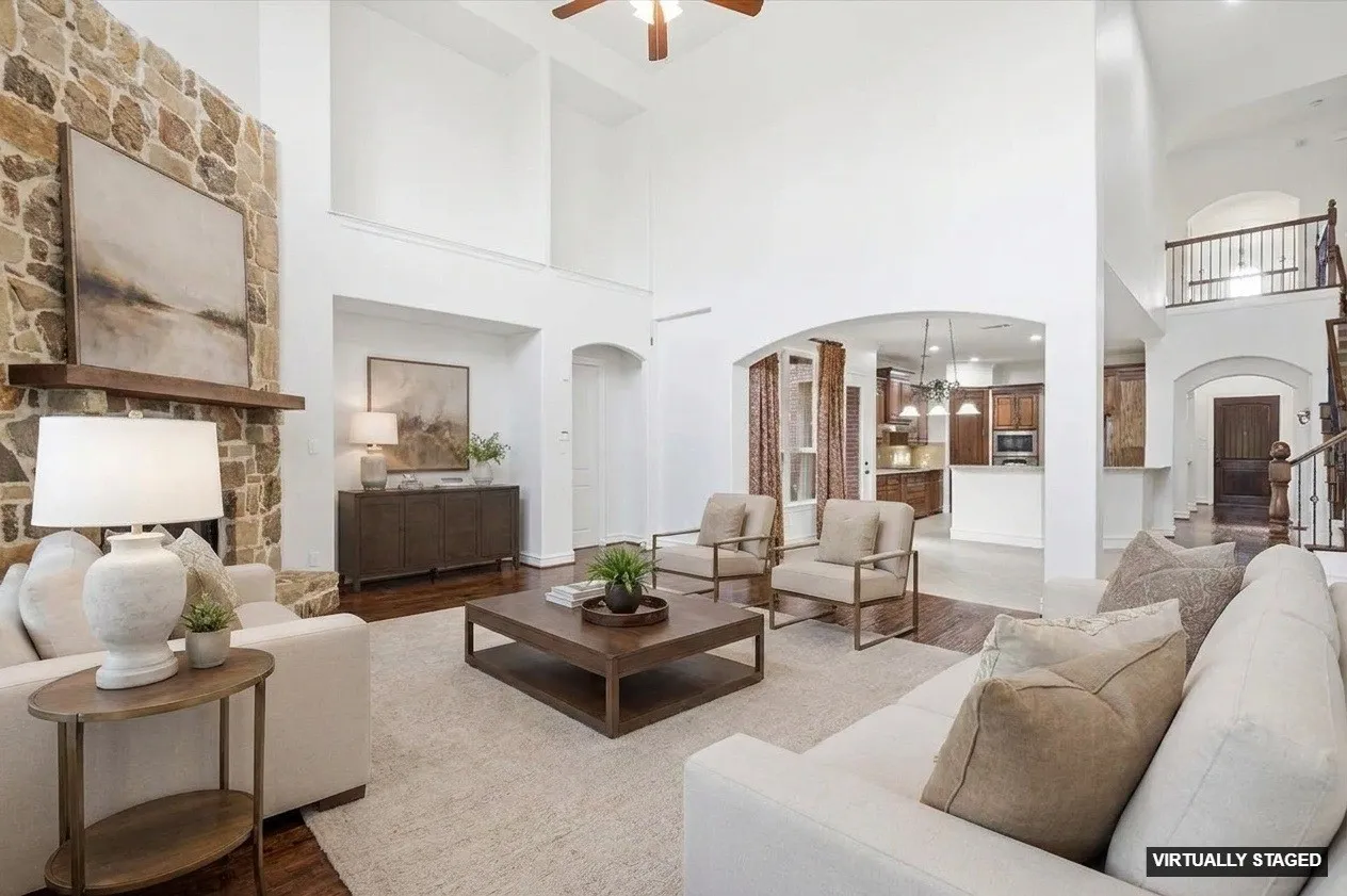 Great room with high ceilings, stone fireplace, wood-finish flooring, and arched doorways