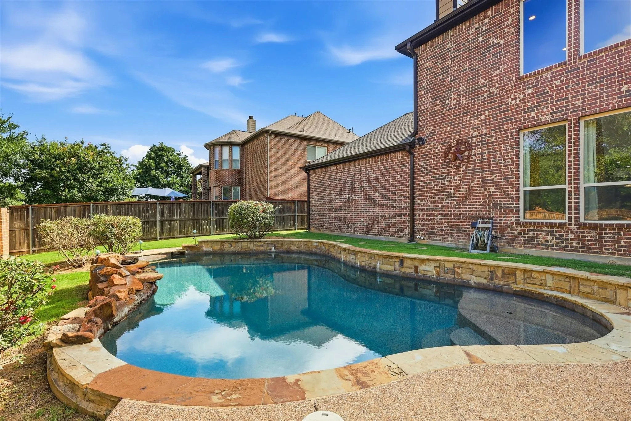Curved swimming pool with stone coping and rock water feature