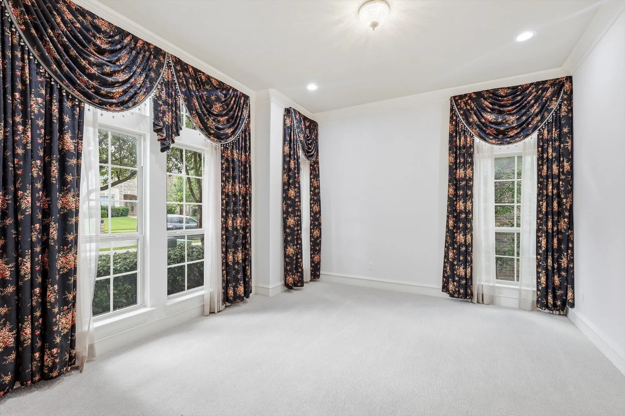 Carpeted room featuring multiple windows with traditional drapery, crown molding, and recessed lighting