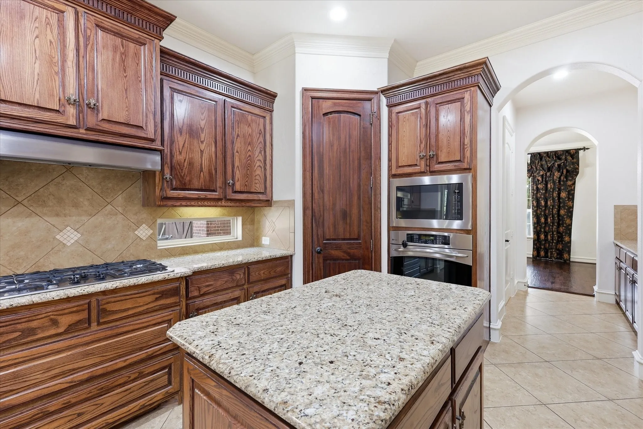 Granite countertops, wood cabinetry, tile flooring, stainless steel built-in appliances, and arched doorways