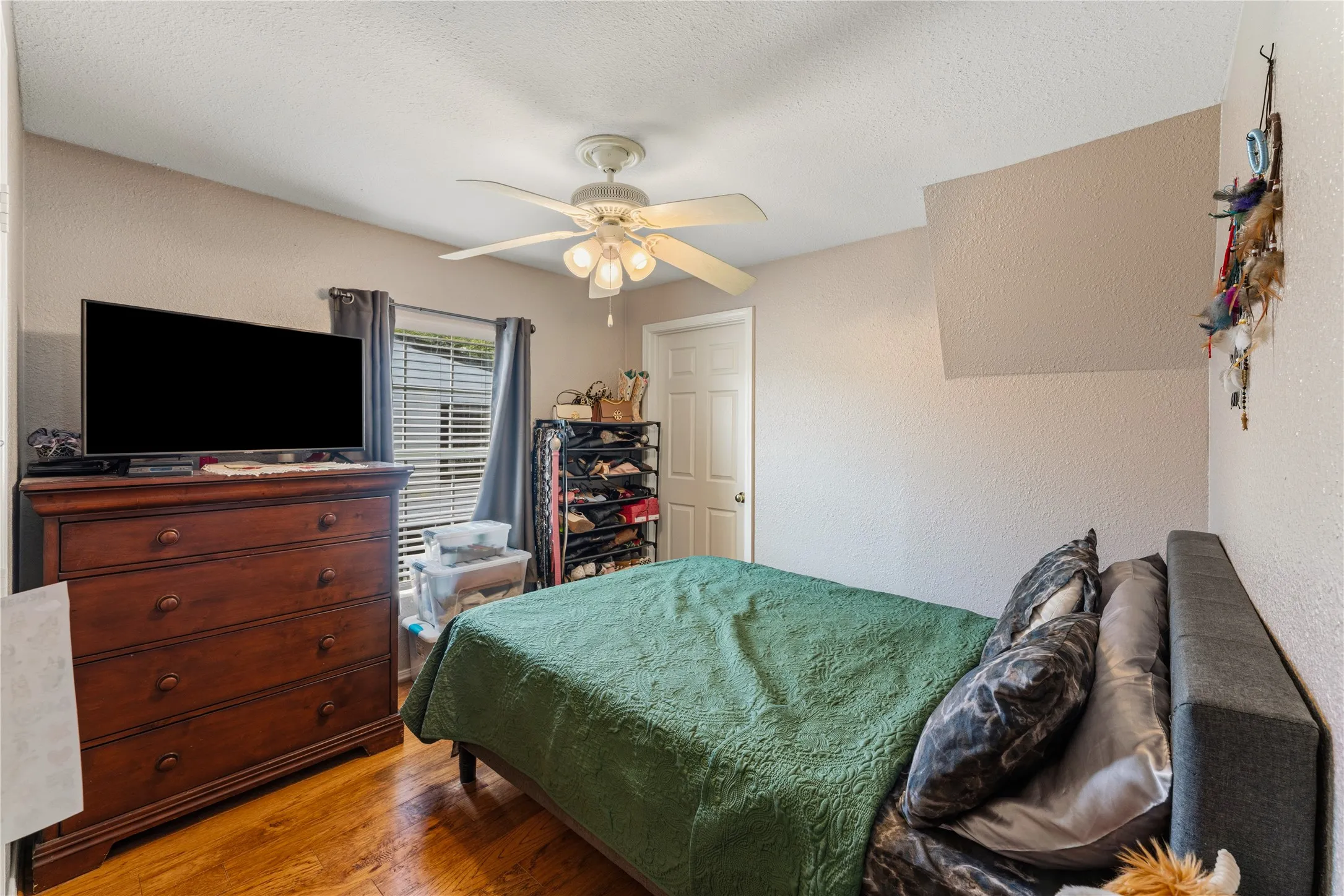 Wood-finish flooring, ceiling fan with integrated lighting, and a white paneled interior door