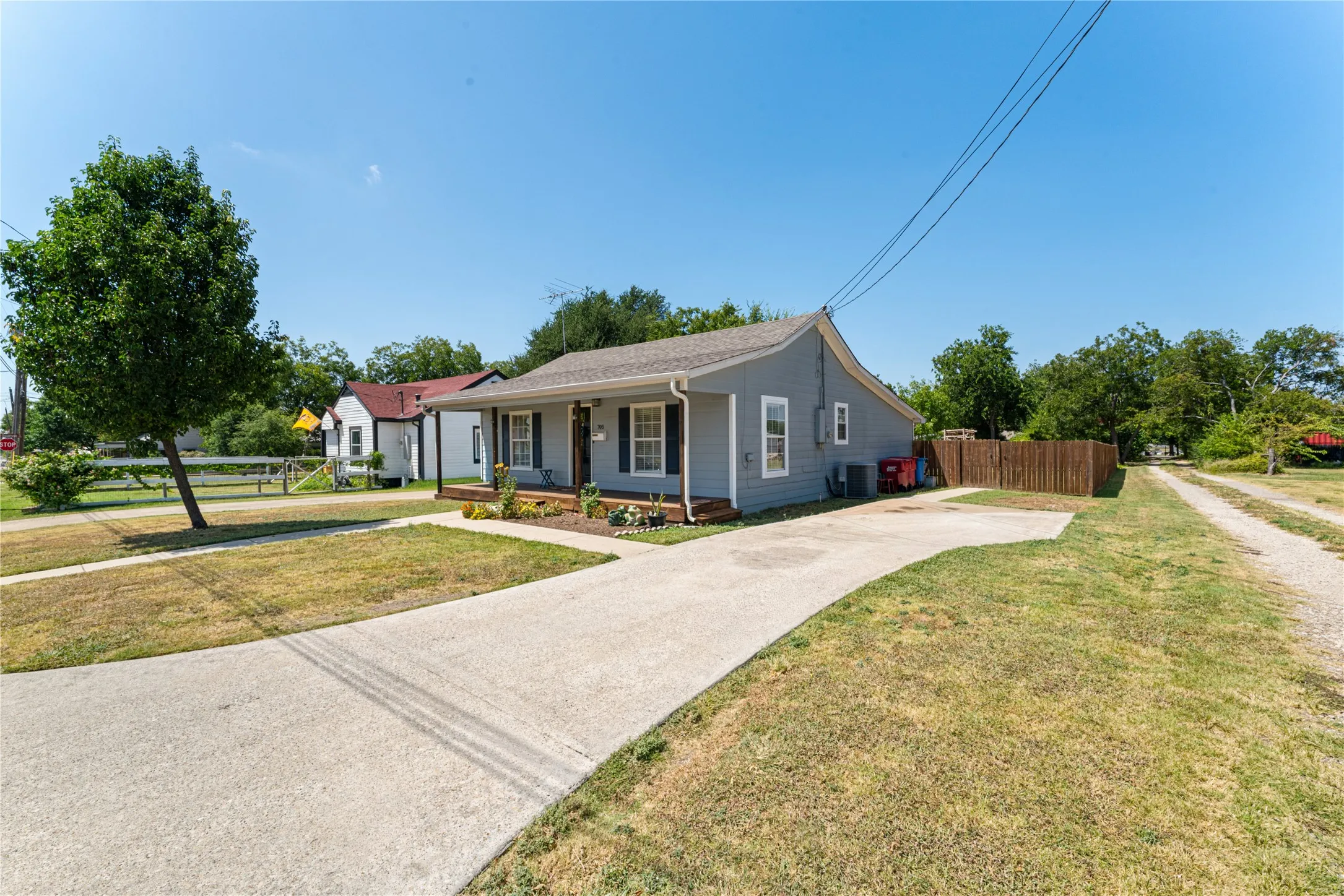 Light gray exterior with contrasting dark shutters, covered front porch, and a concrete driveway