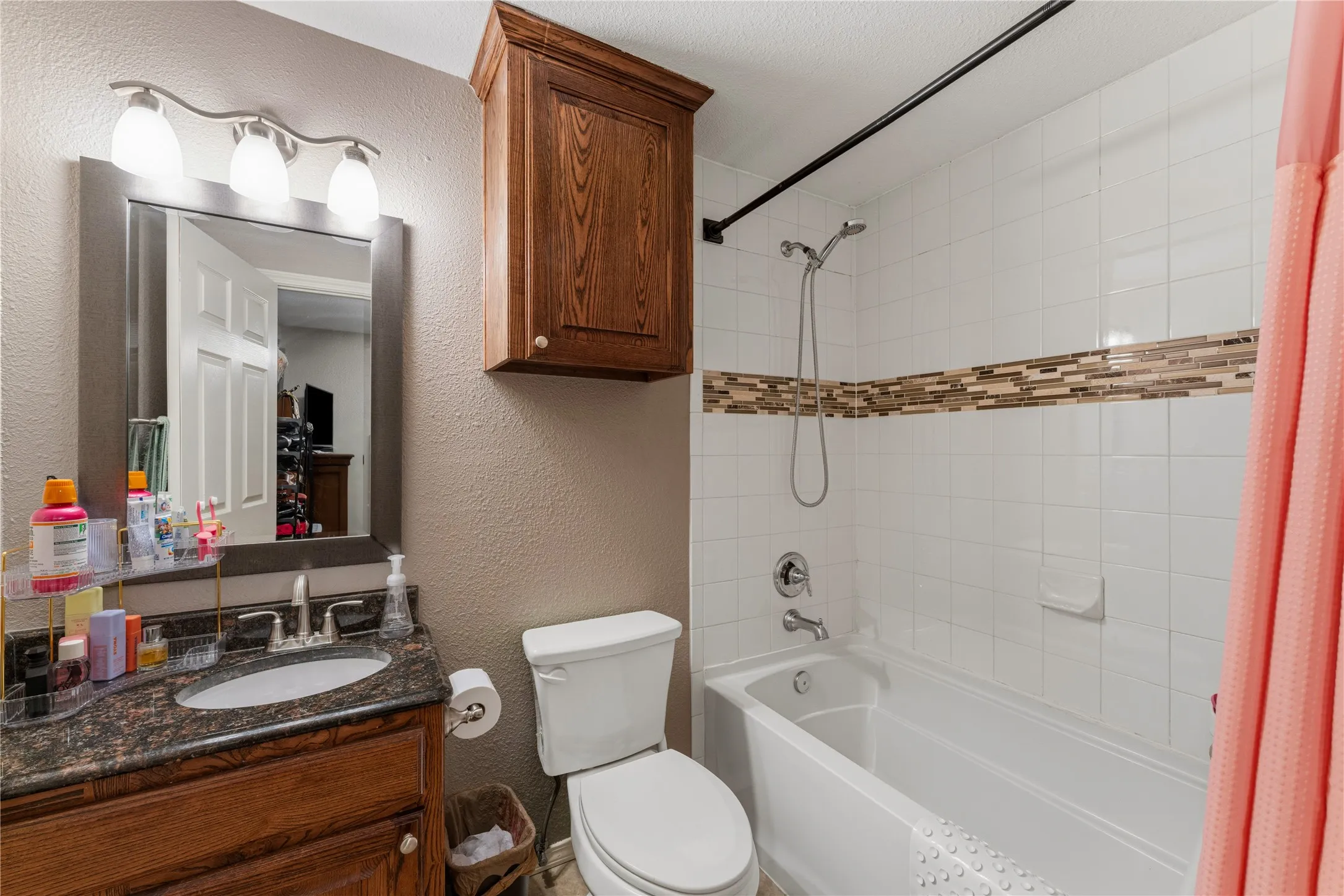 Bathroom featuring a wood-finish vanity with an undermount sink, granite-look countertop, and a framed mirror