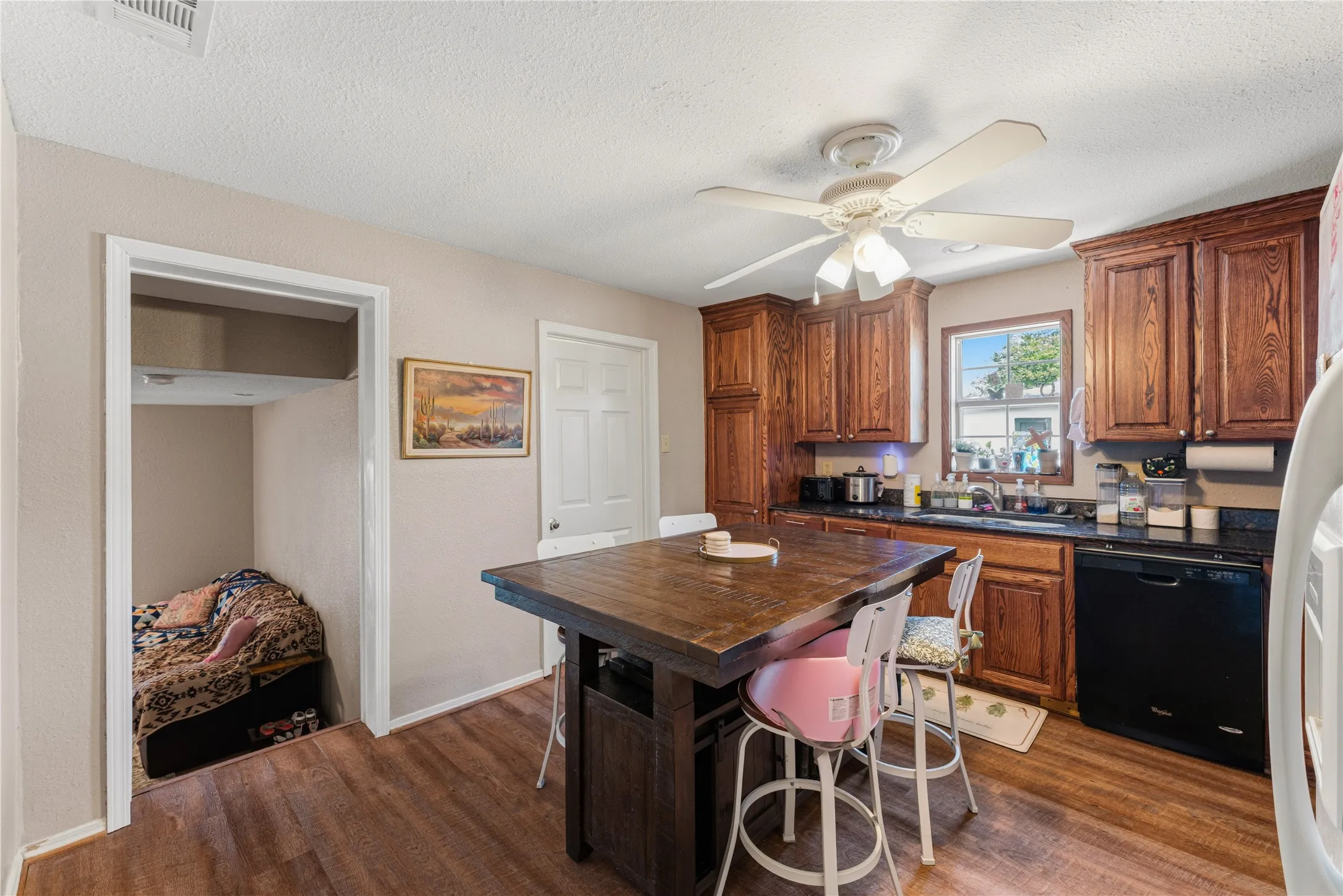 Kitchen featuring wood-finish flooring, dark cabinetry, and black countertops