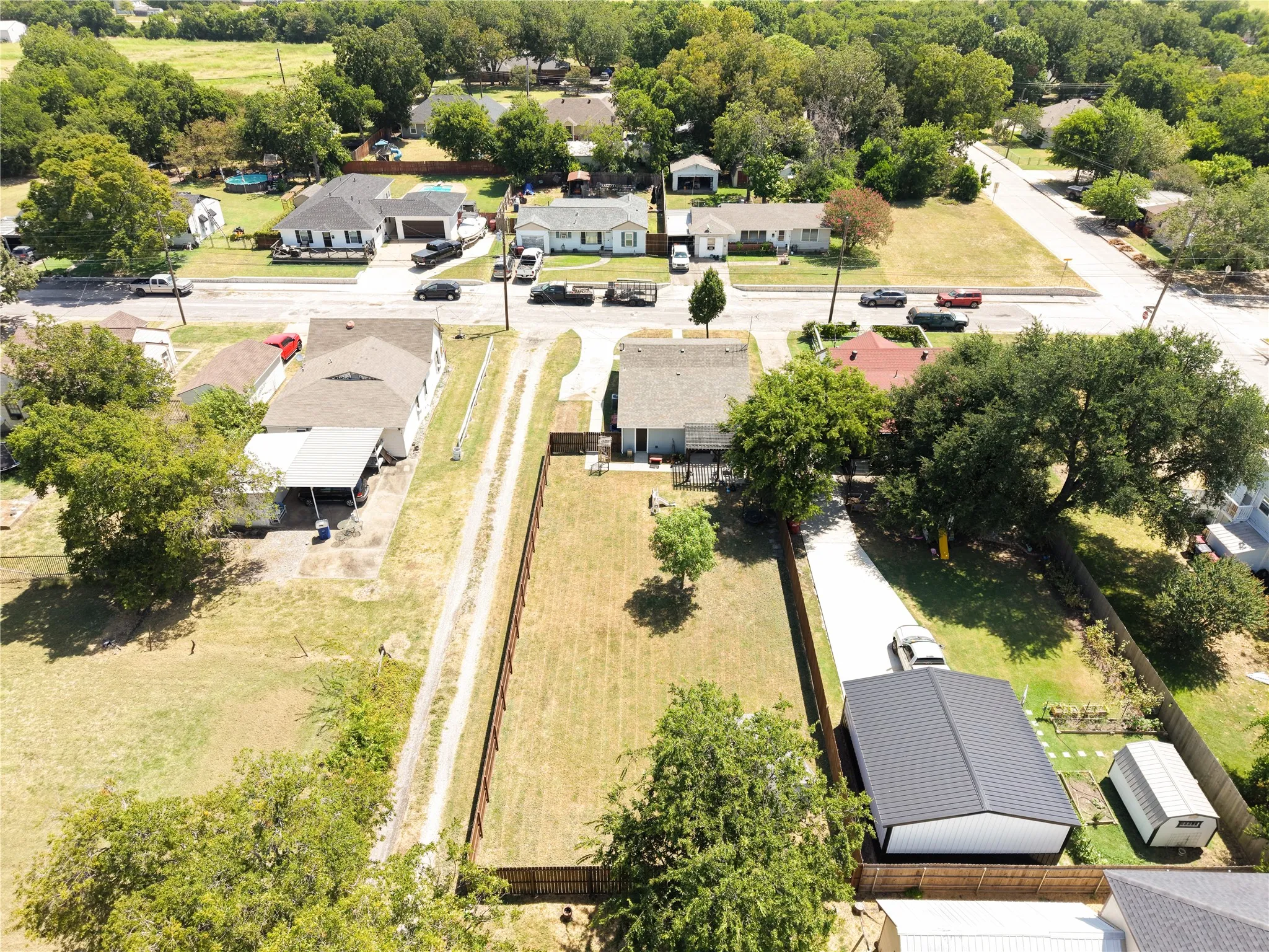 Expansive property featuring a metal carport, gravel driveway, and a fenced yard