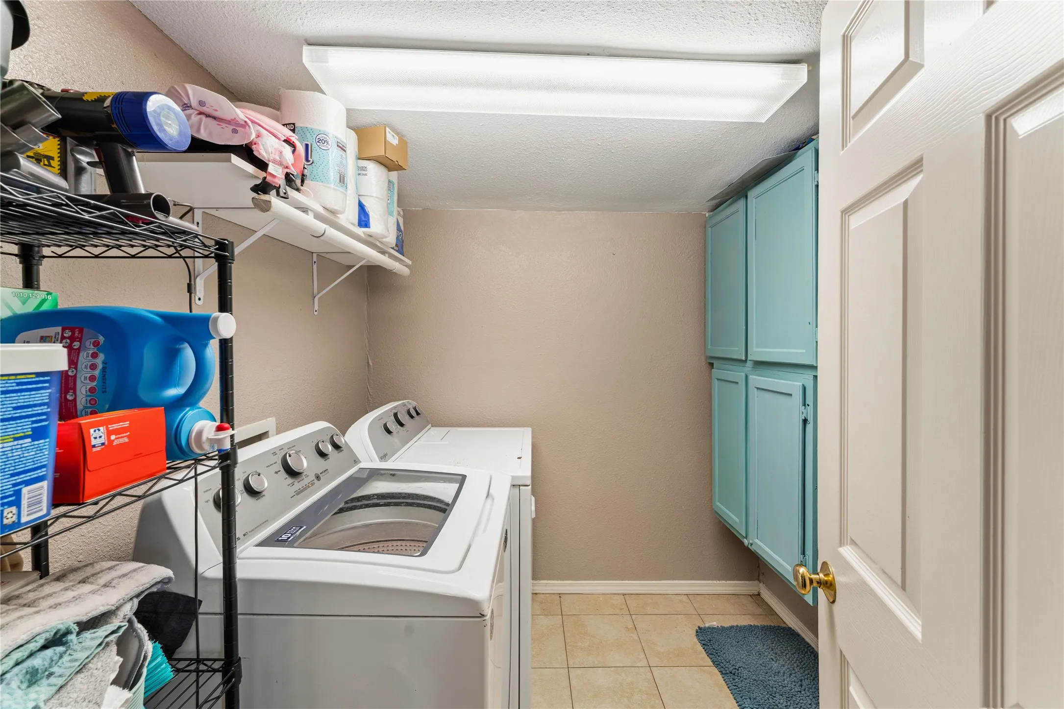 Laundry area featuring built-in cabinetry, wall shelving, and tile flooring