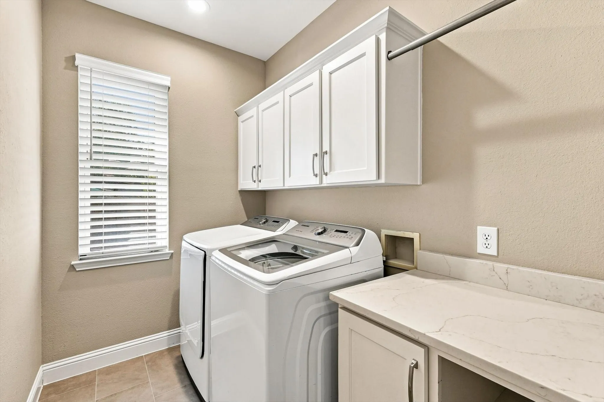 White shaker-style cabinetry with crown molding, a clothes hanging rod, a stone-finish countertop, and tile flooring