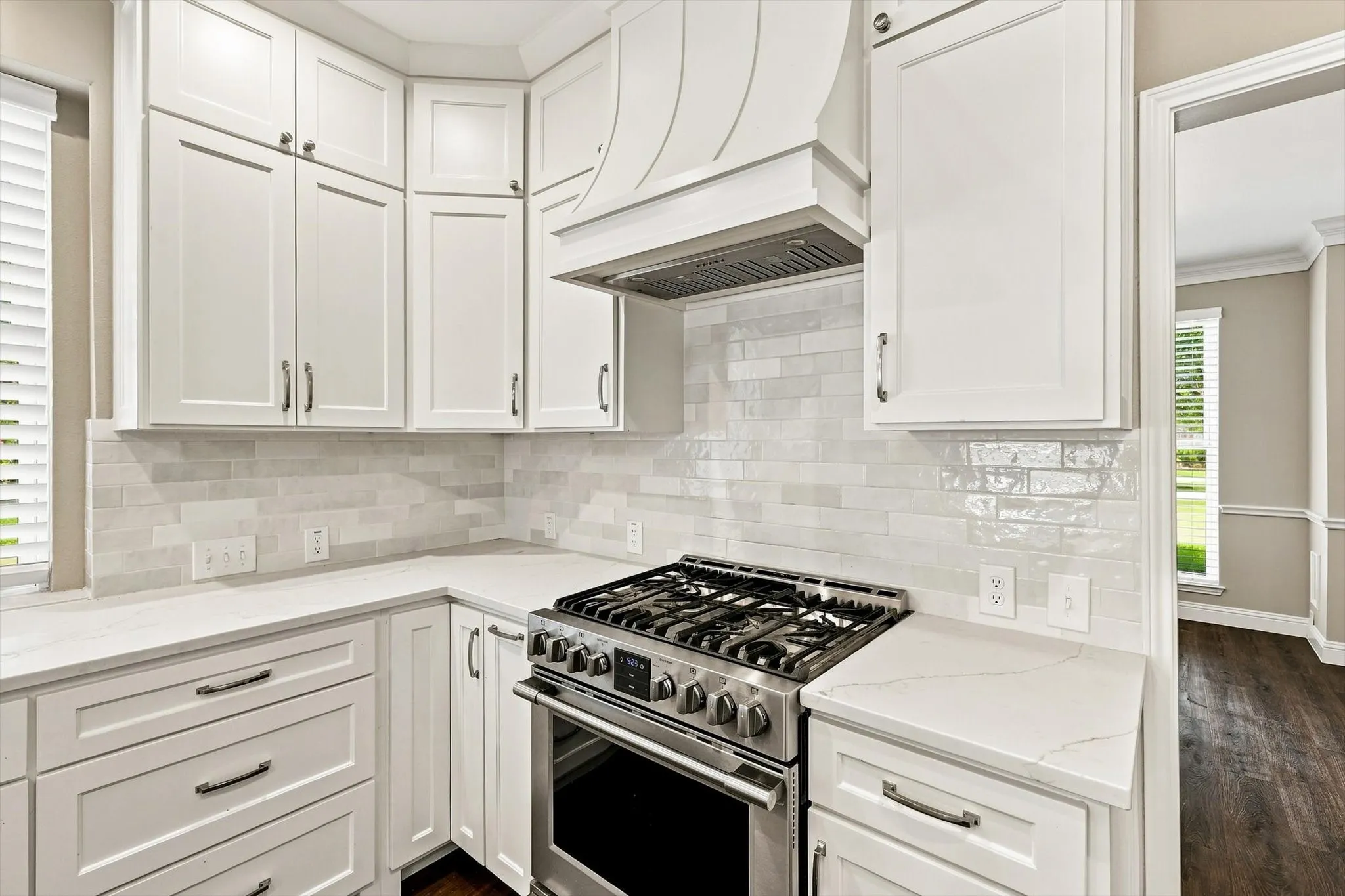 White shaker-style cabinetry, stainless steel range with gas burners, white subway tile backsplash, and light-toned countertops