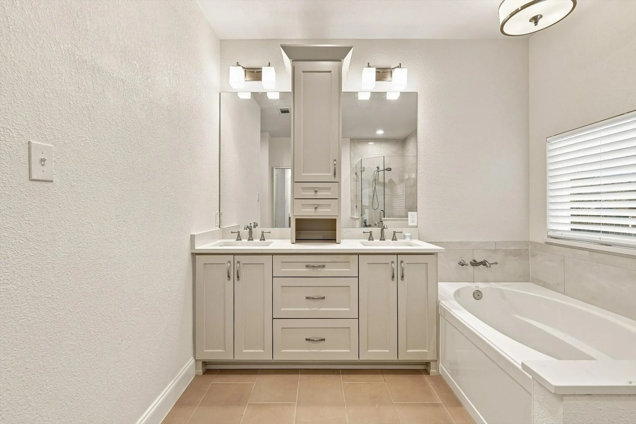 Dual vanity with undermount sinks, light-toned cabinetry, and a built-in storage tower