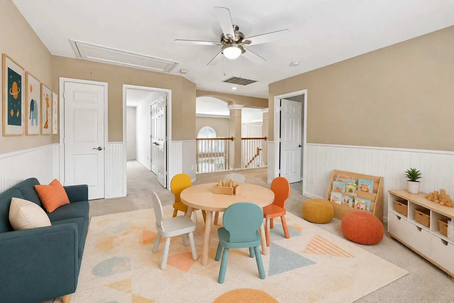 Expansive room featuring a ceiling fan, white paneled wainscoting, and carpeted flooring