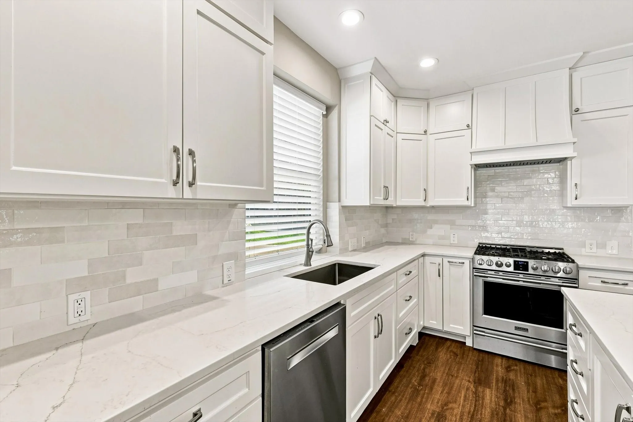 Modern kitchen featuring white shaker cabinetry, stainless steel appliances, a subway tile backsplash, light-toned countertops, and wood-finish flooring