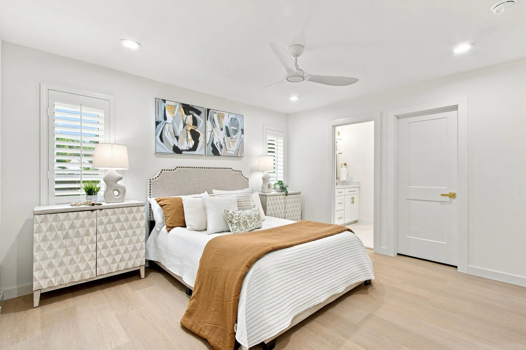 Light wood-finish flooring, recessed lighting, and a ceiling fan are featured in this room with white walls