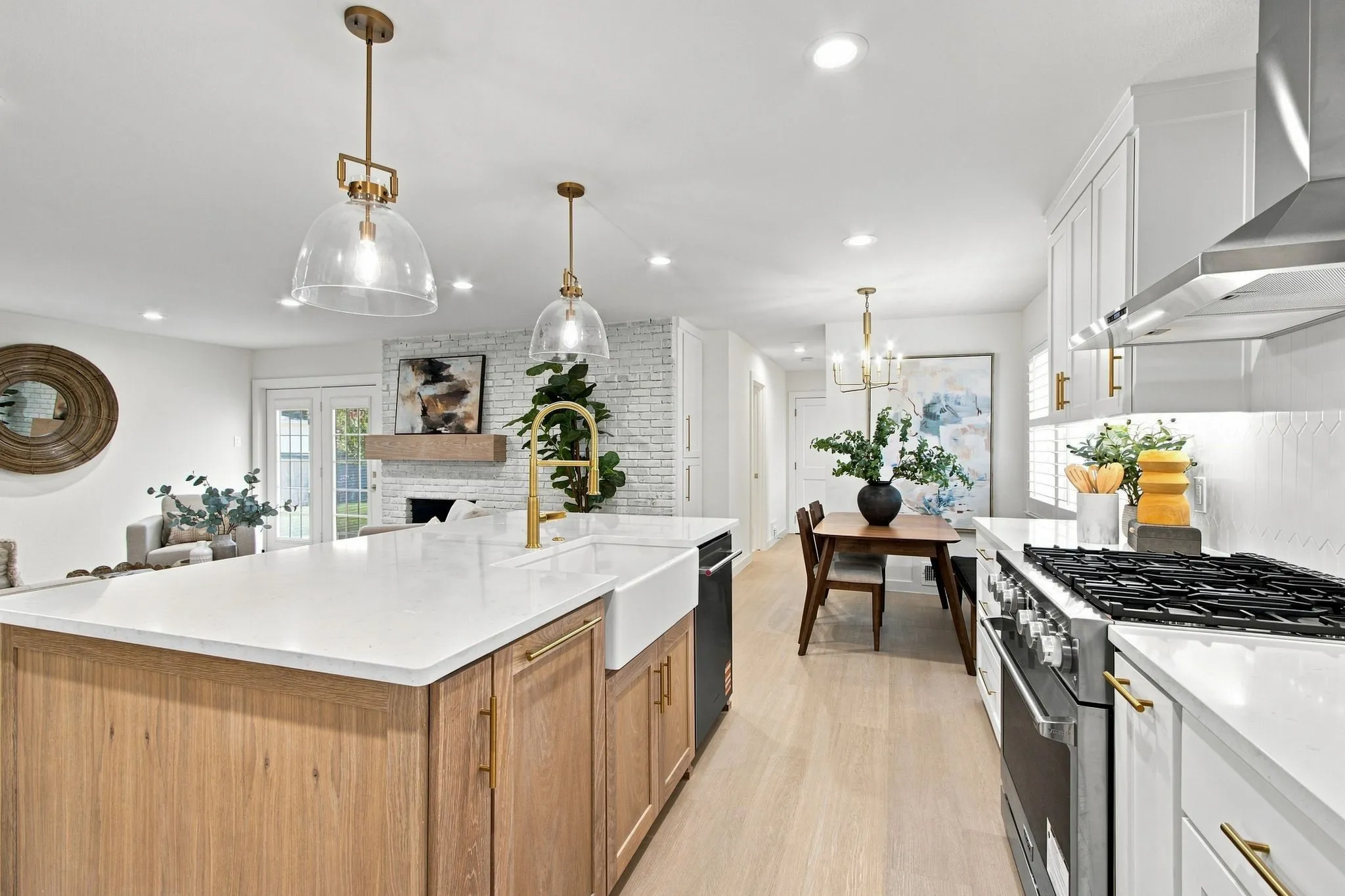 Open-concept kitchen with a large central island, white shaker cabinetry, stainless steel appliances, and wood-finish flooring