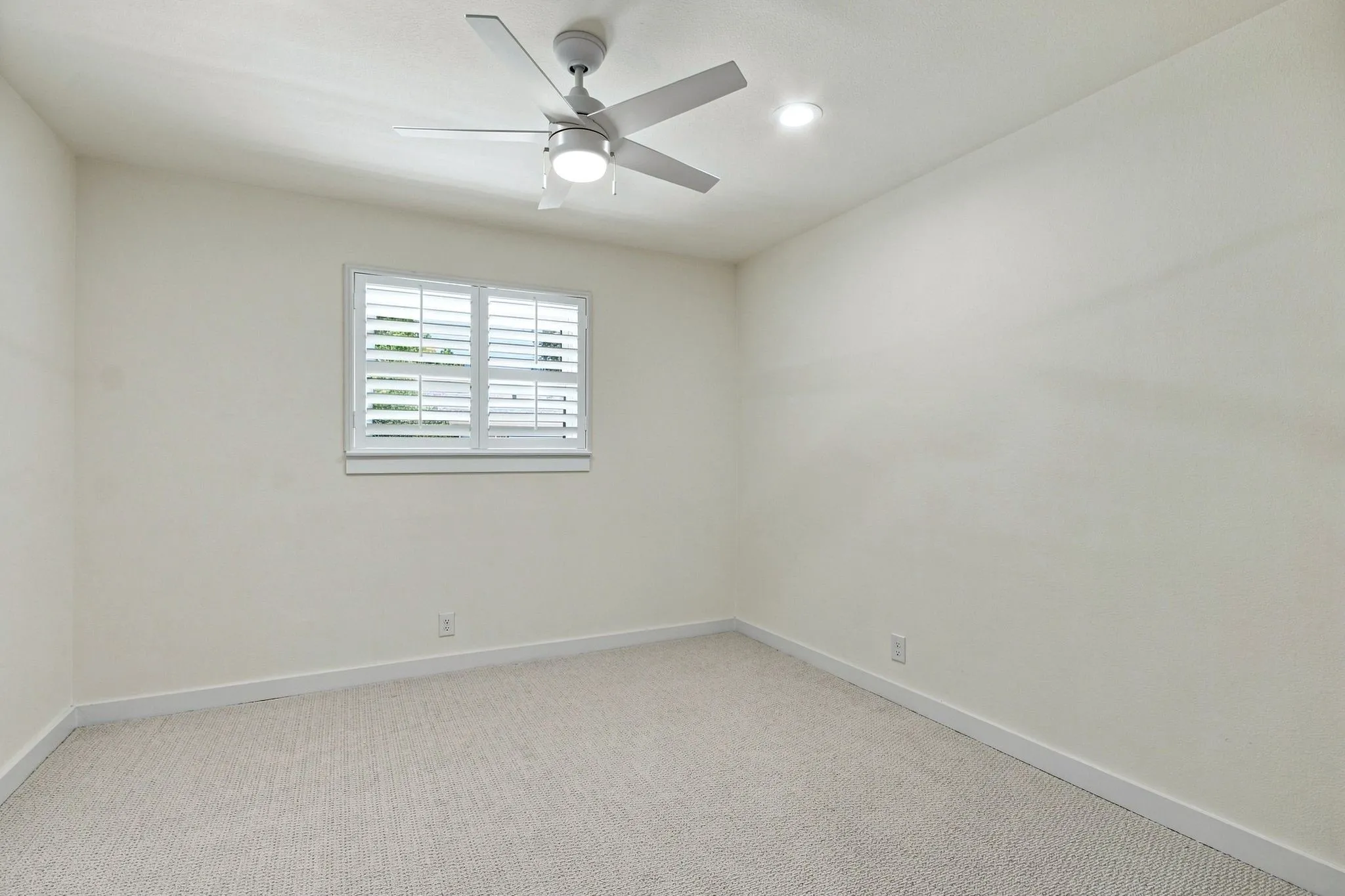Recessed lighting, window with plantation shutters, ceiling fan with integrated light, and neutral wall paint