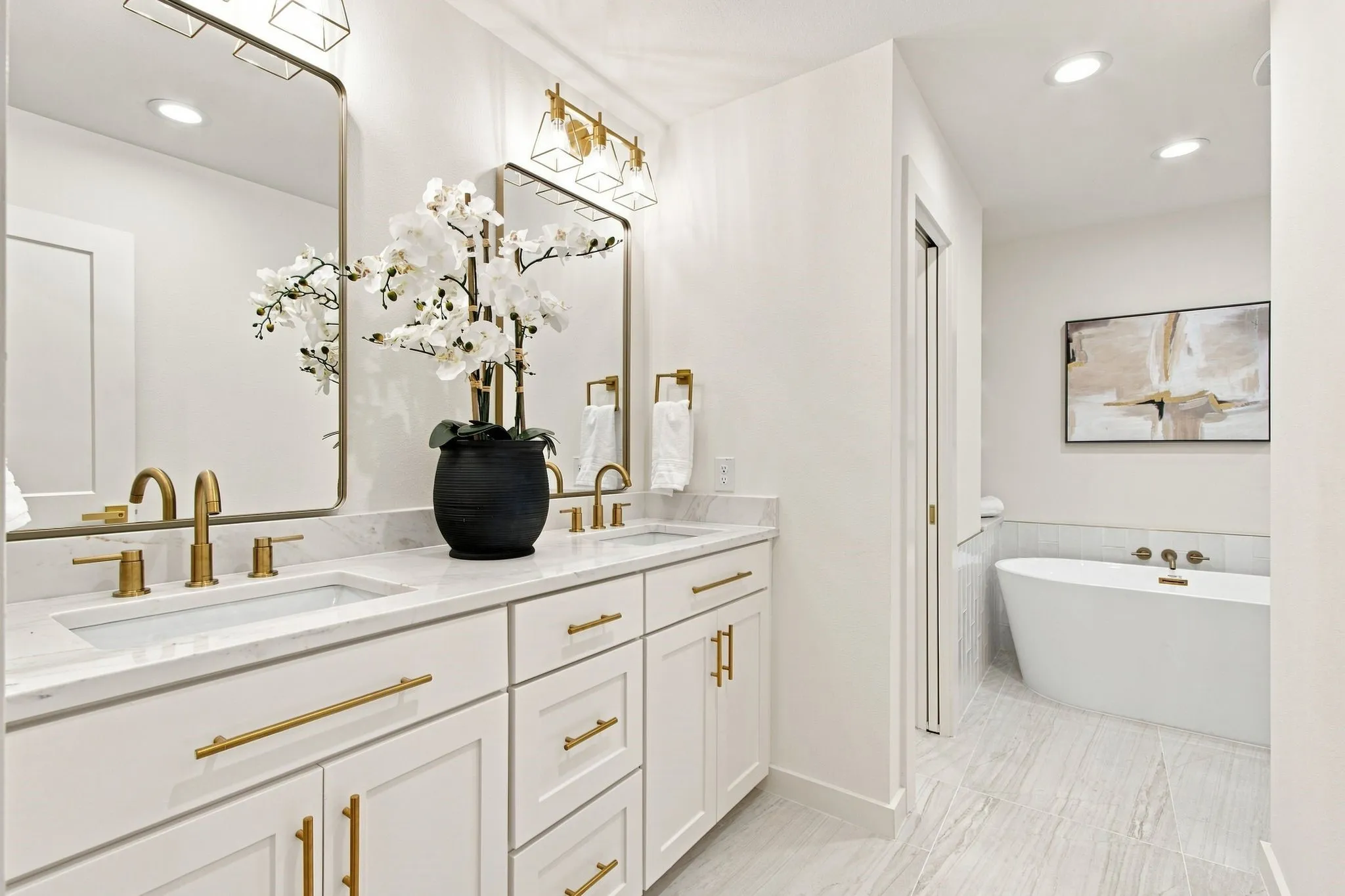 Dual vanity with undermount sinks, white cabinetry, and gold-finish hardware