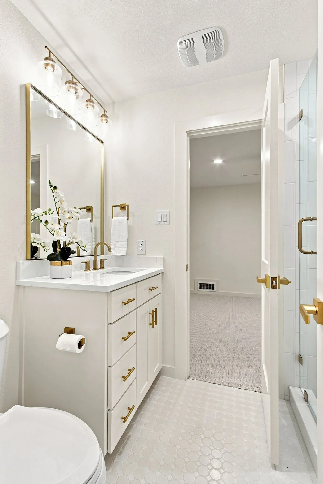 White vanity with gold-finish hardware, quartz countertop, and integrated sink