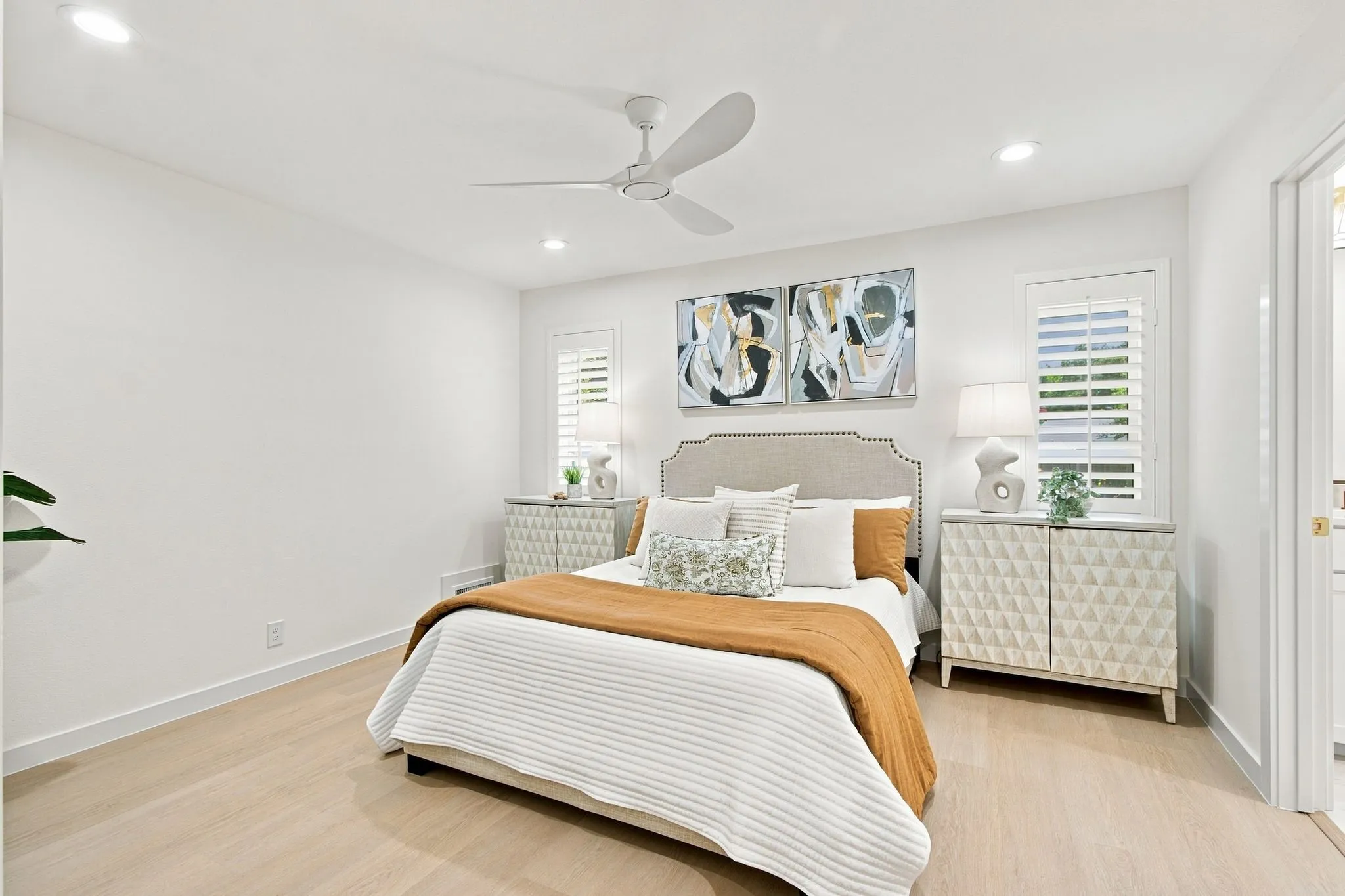 Recessed lighting, wood-finish flooring, white walls, ceiling fan, and window with plantation shutters