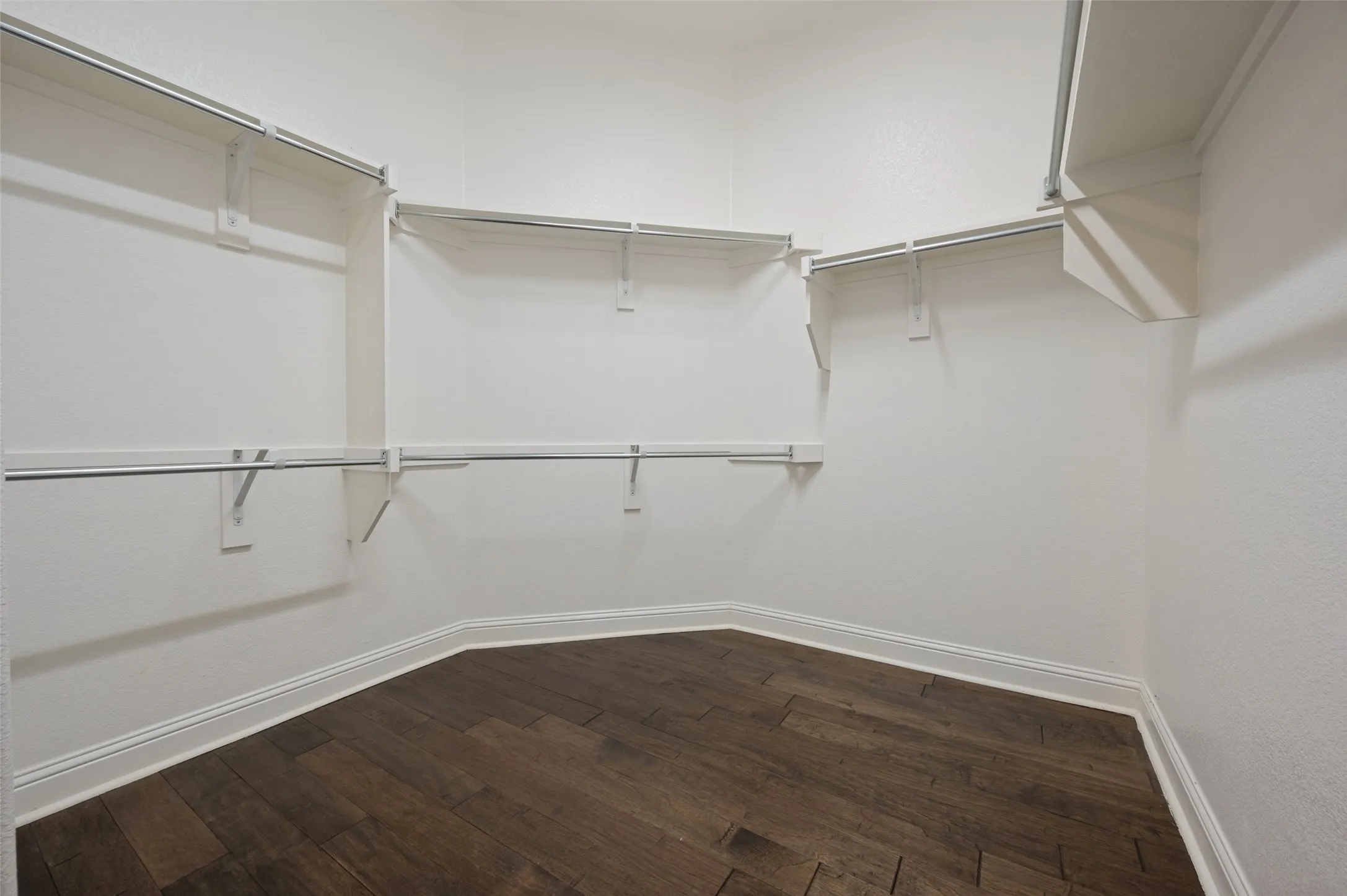 Walk-in closet featuring wood-finish flooring and built-in shelving with hanging rods