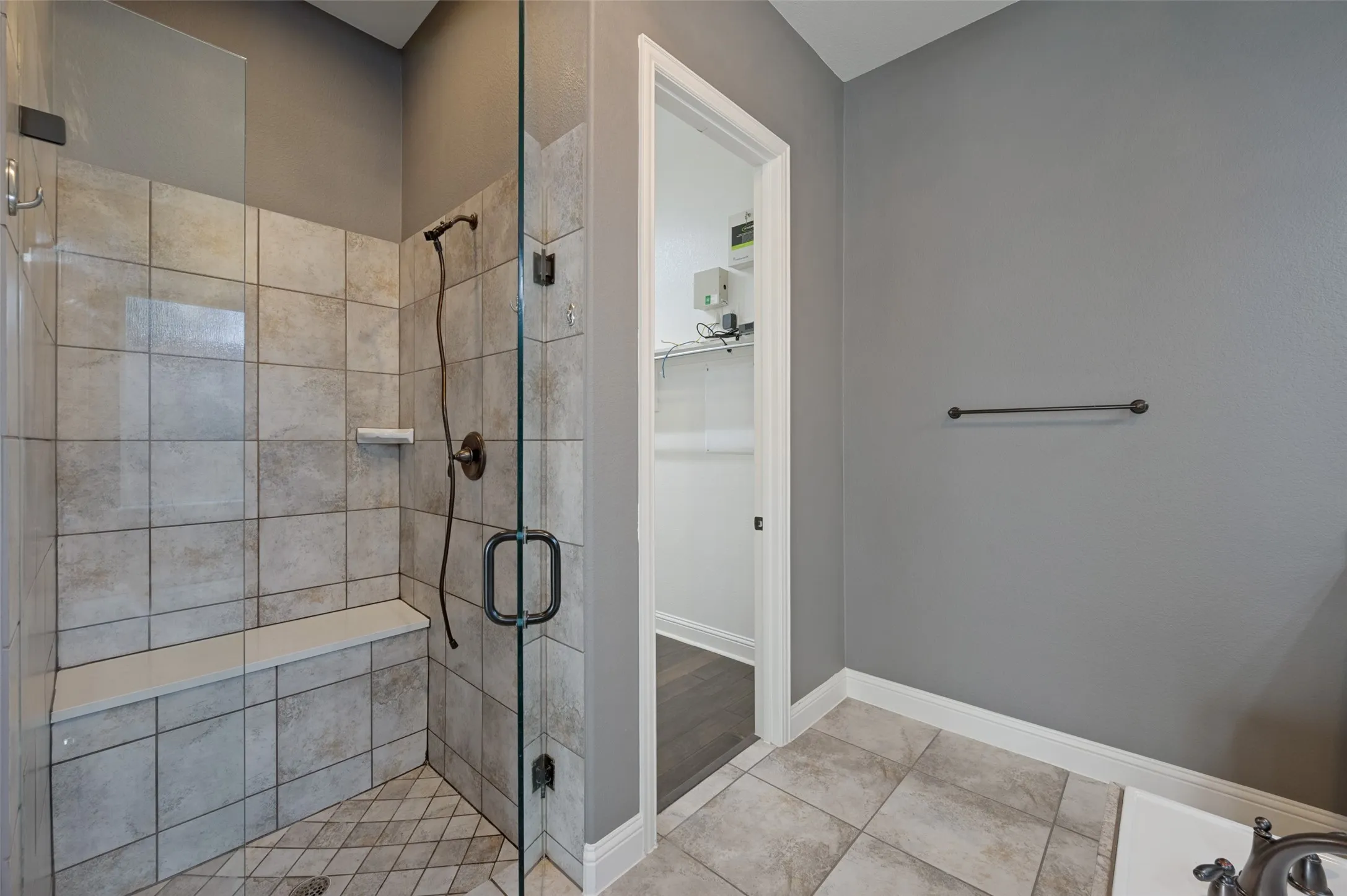 Glass-enclosed shower with tile surround, built-in bench, and oil-rubbed bronze fixtures