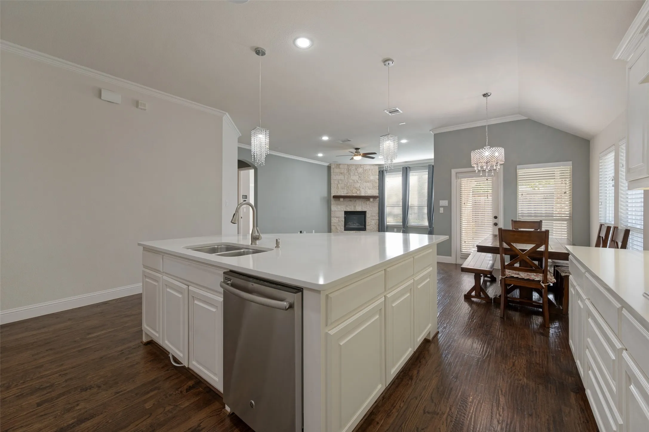 Kitchen island with white countertops, integrated sink, and stainless steel dishwasher