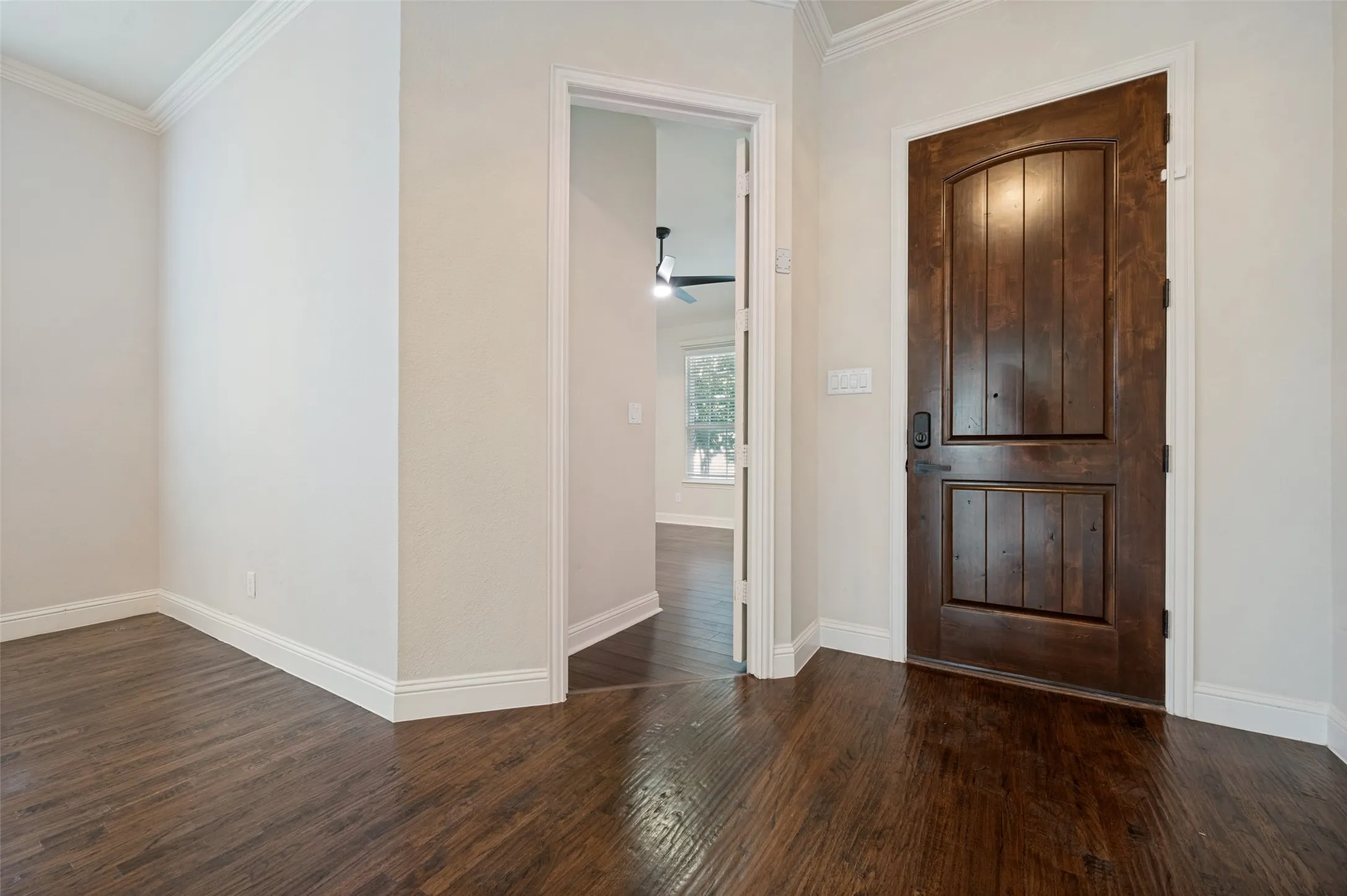 Rich wood-finish flooring, white trim, and crown molding