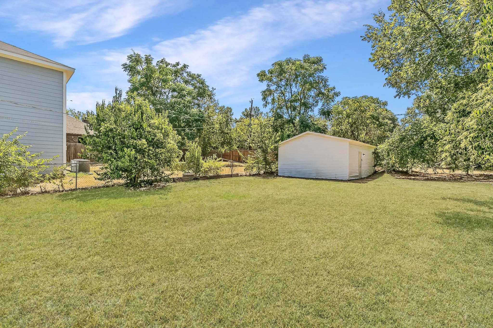Expansive lawn area, mature trees, privacy fencing, detached storage shed, and side exterior siding
