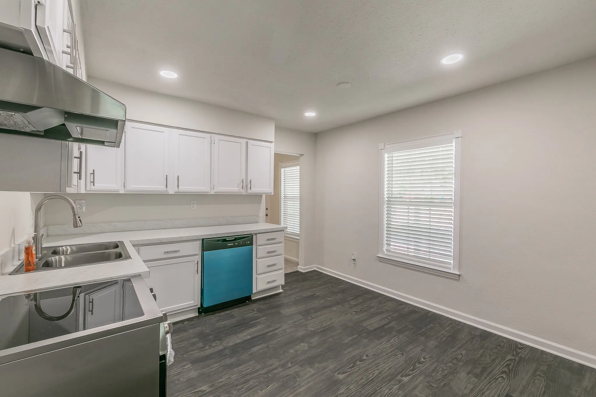 White cabinetry with brushed nickel hardware, stainless steel sink, wood-finish flooring, and recessed lighting