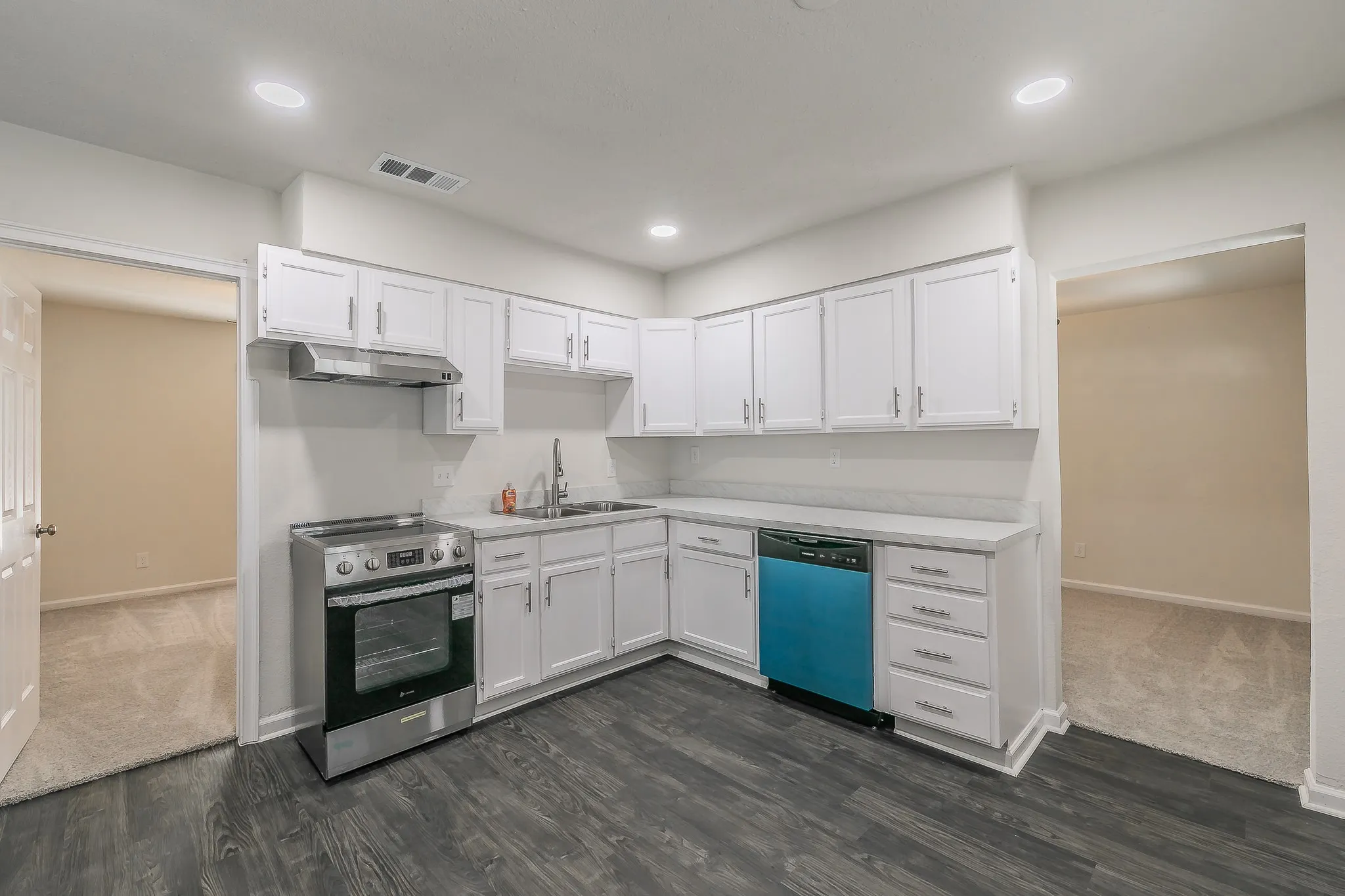 Kitchen featuring wood-finish flooring, white cabinetry, a stainless steel range, and a built-in dishwasher