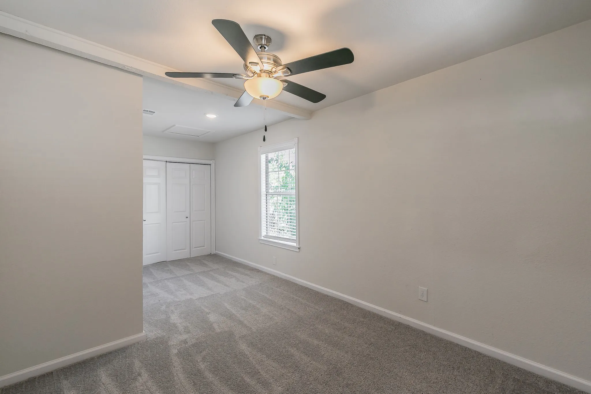 Recessed lighting, ceiling fan with light fixture, gray carpet, white walls, and bi-fold closet doors