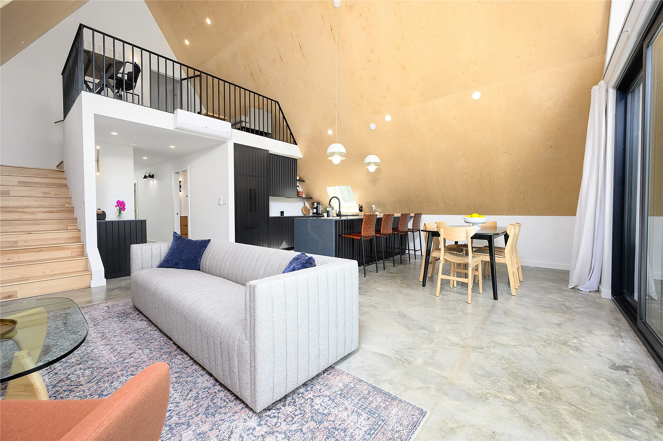 Soaring ceilings with modern wood detailing, low-maintenance concrete flooring, stairs to the primary bedroom, en-suite and loft area