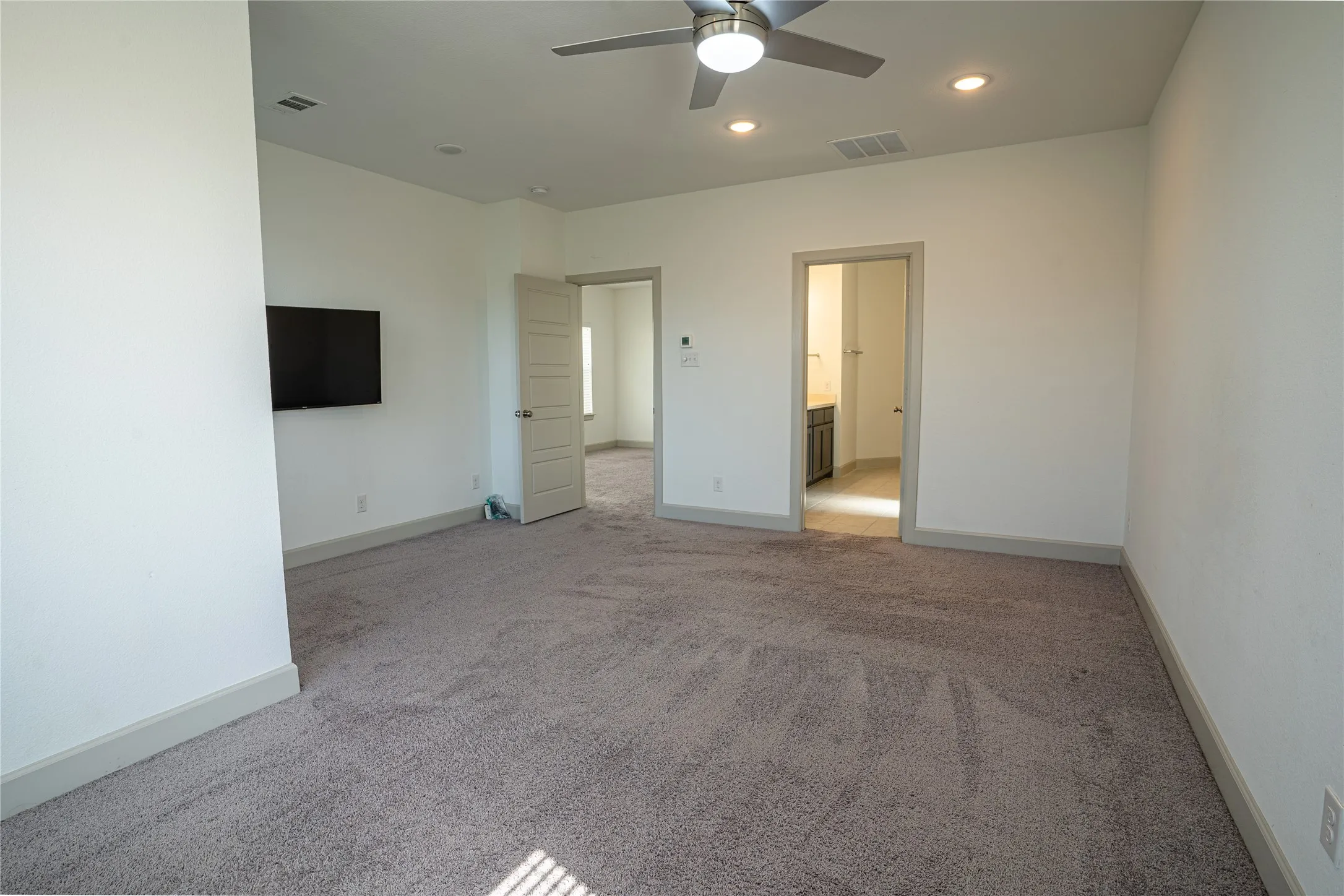 Neutral-toned carpet flooring, a ceiling fan with integrated lighting, recessed lighting, and white trim