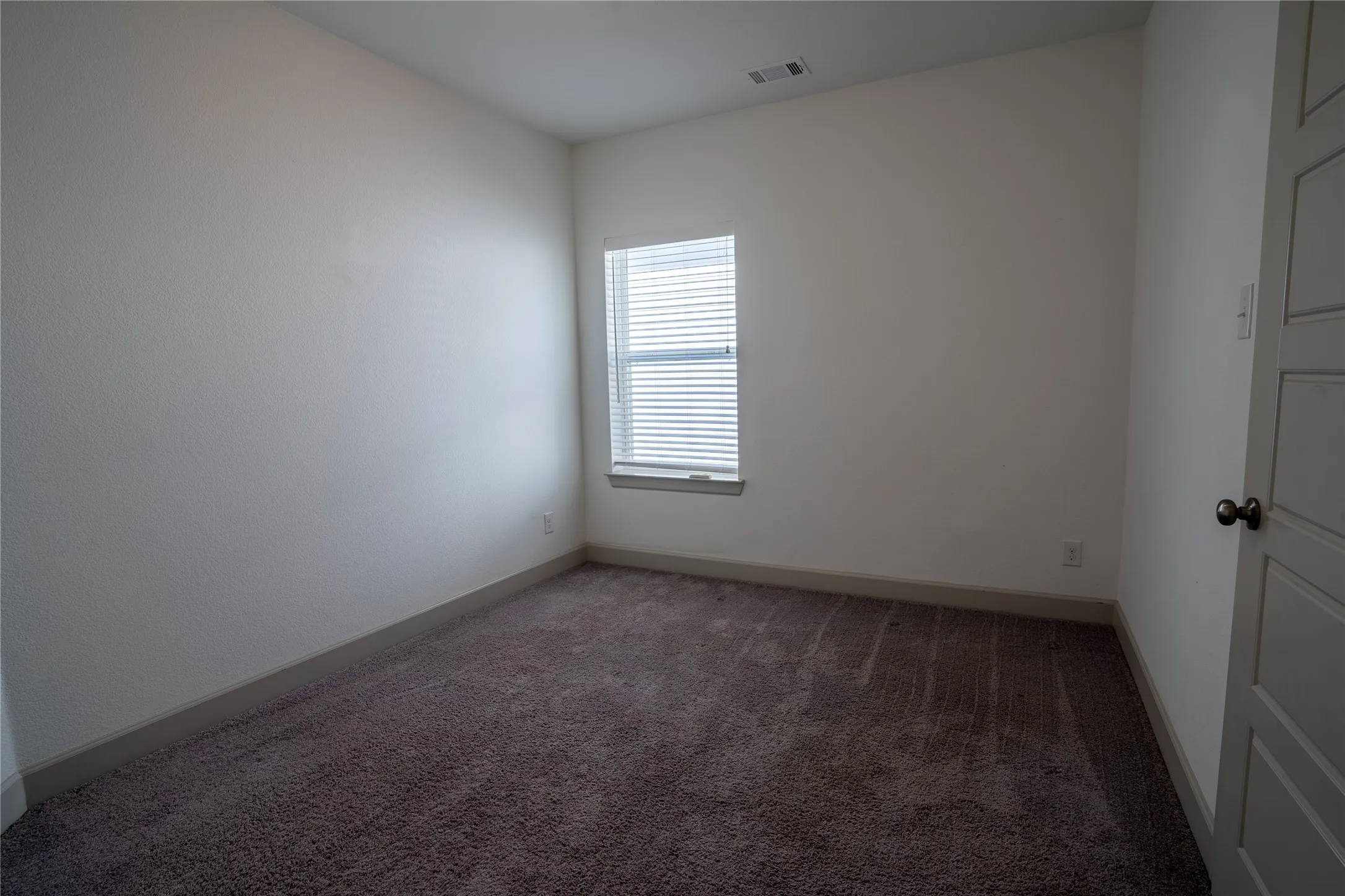 Window with horizontal blinds and textured carpet