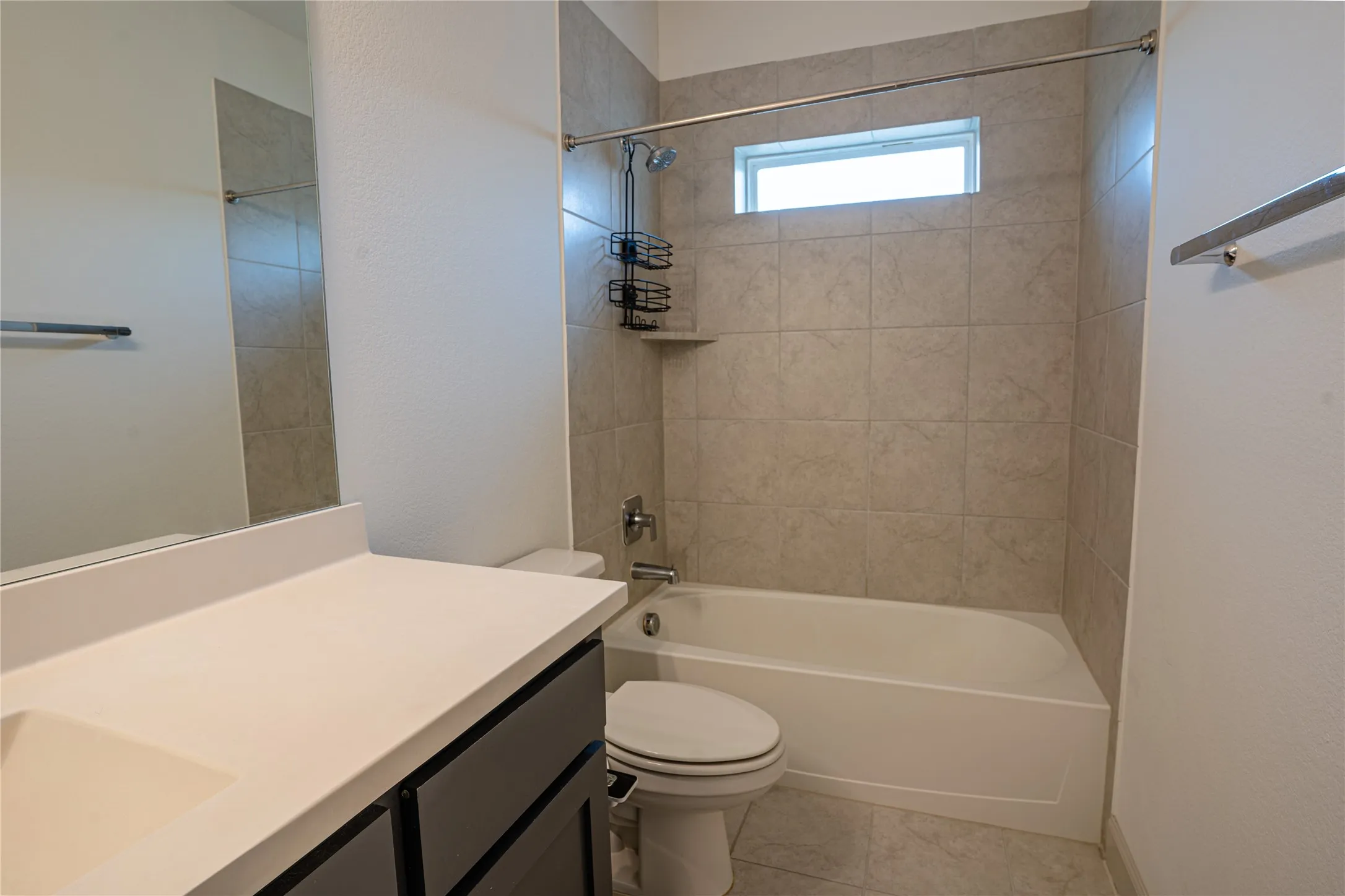 Bathroom with an integrated sink vanity, a framed mirror, a tub-shower combination with tiled surround, and a compact window