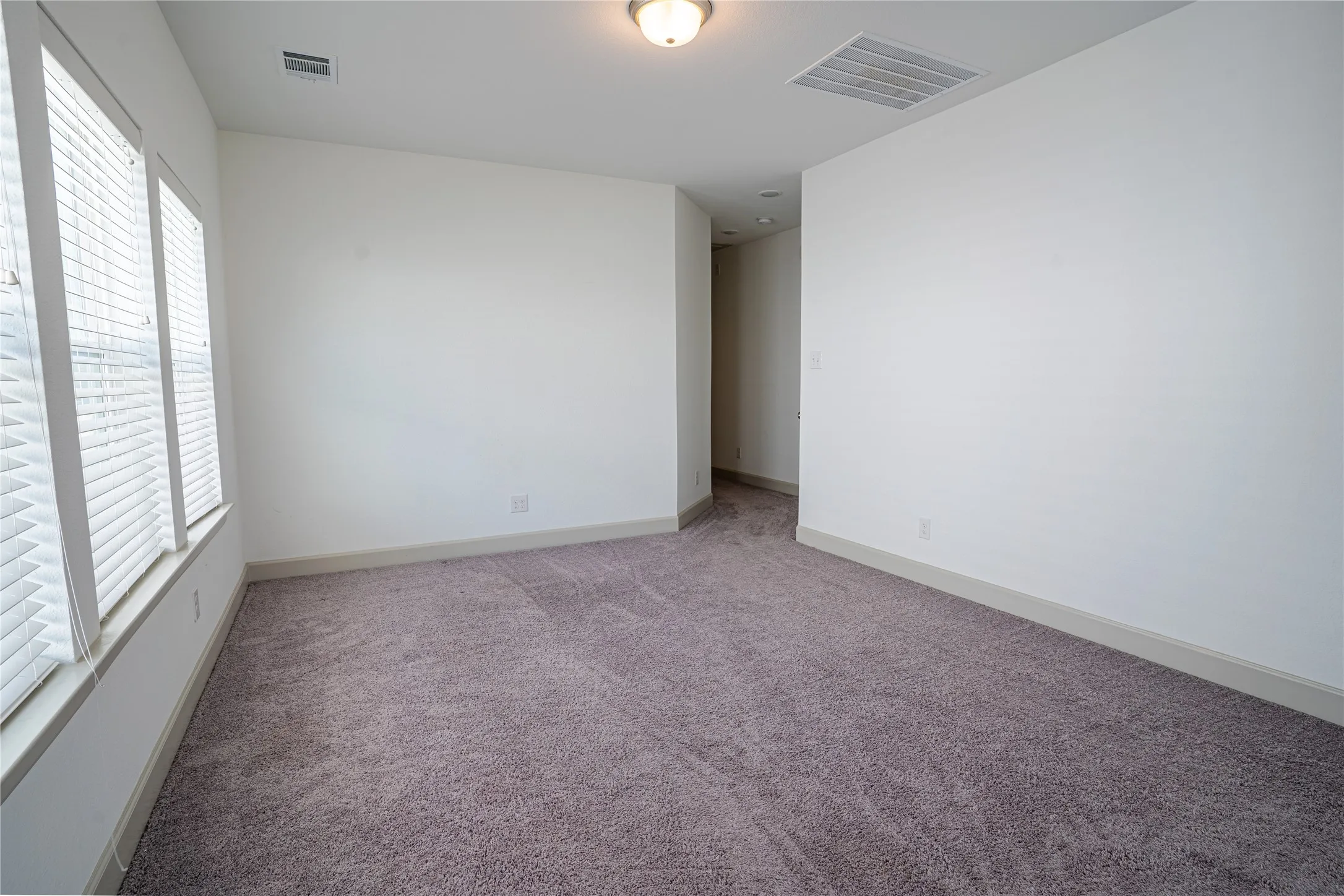 Carpeted flooring, multiple windows with blinds, recessed lighting, and white wall finishes