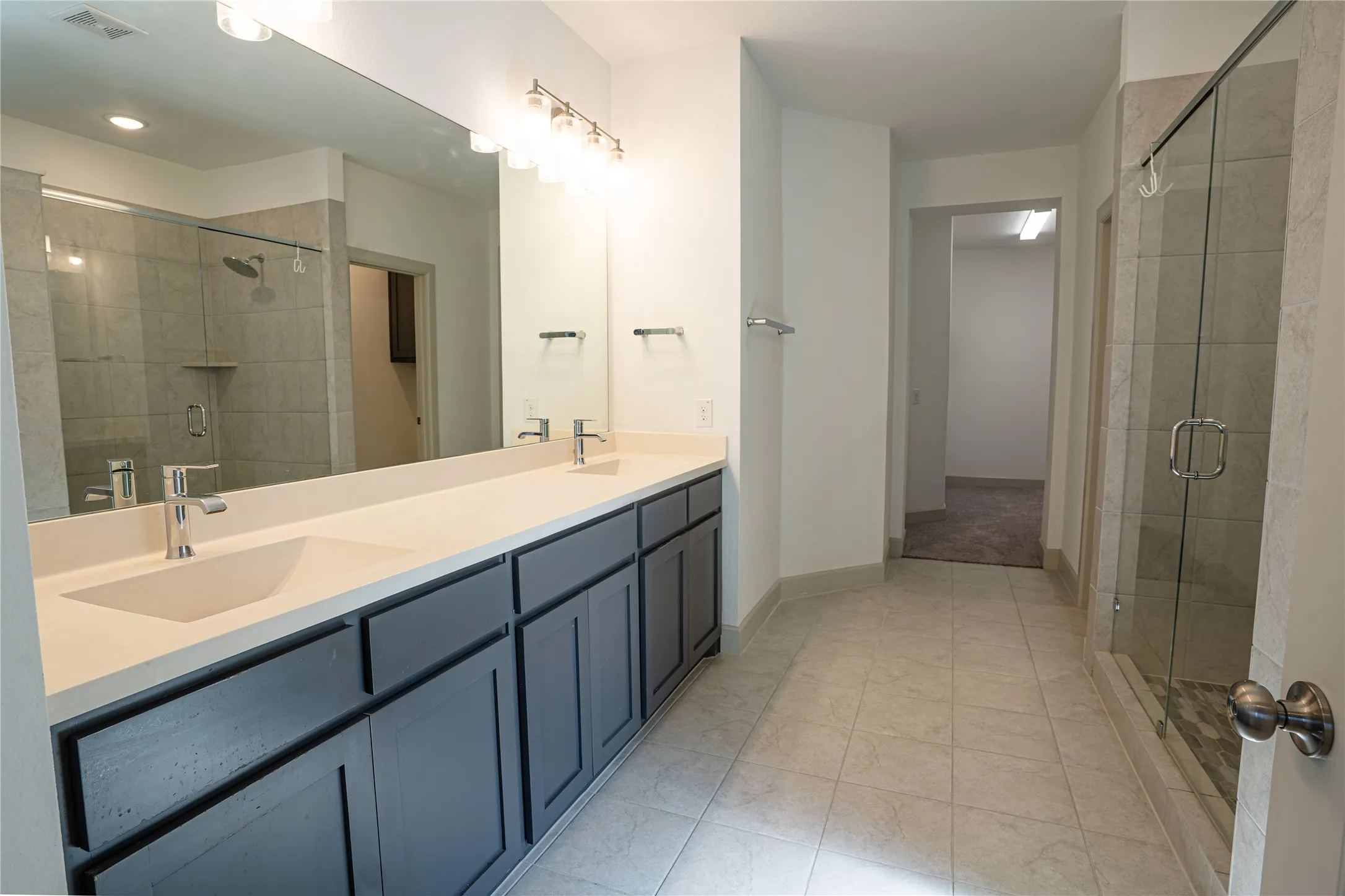 Expansive bathroom featuring a dual vanity with a light countertop, dark cabinetry, and chrome fixtures