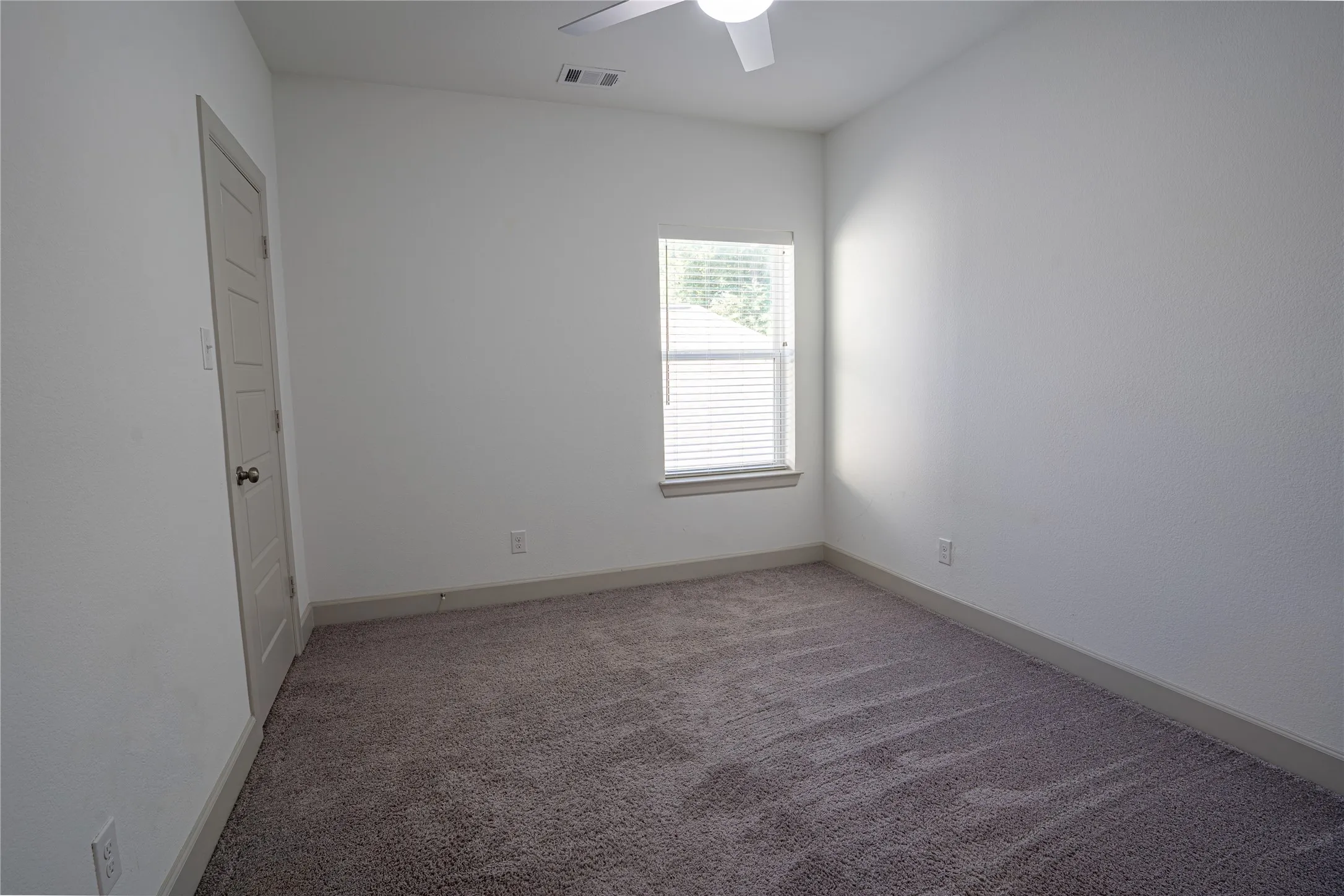 Neutral wall paint, carpeted flooring, window with blinds, ceiling fan, and panel door