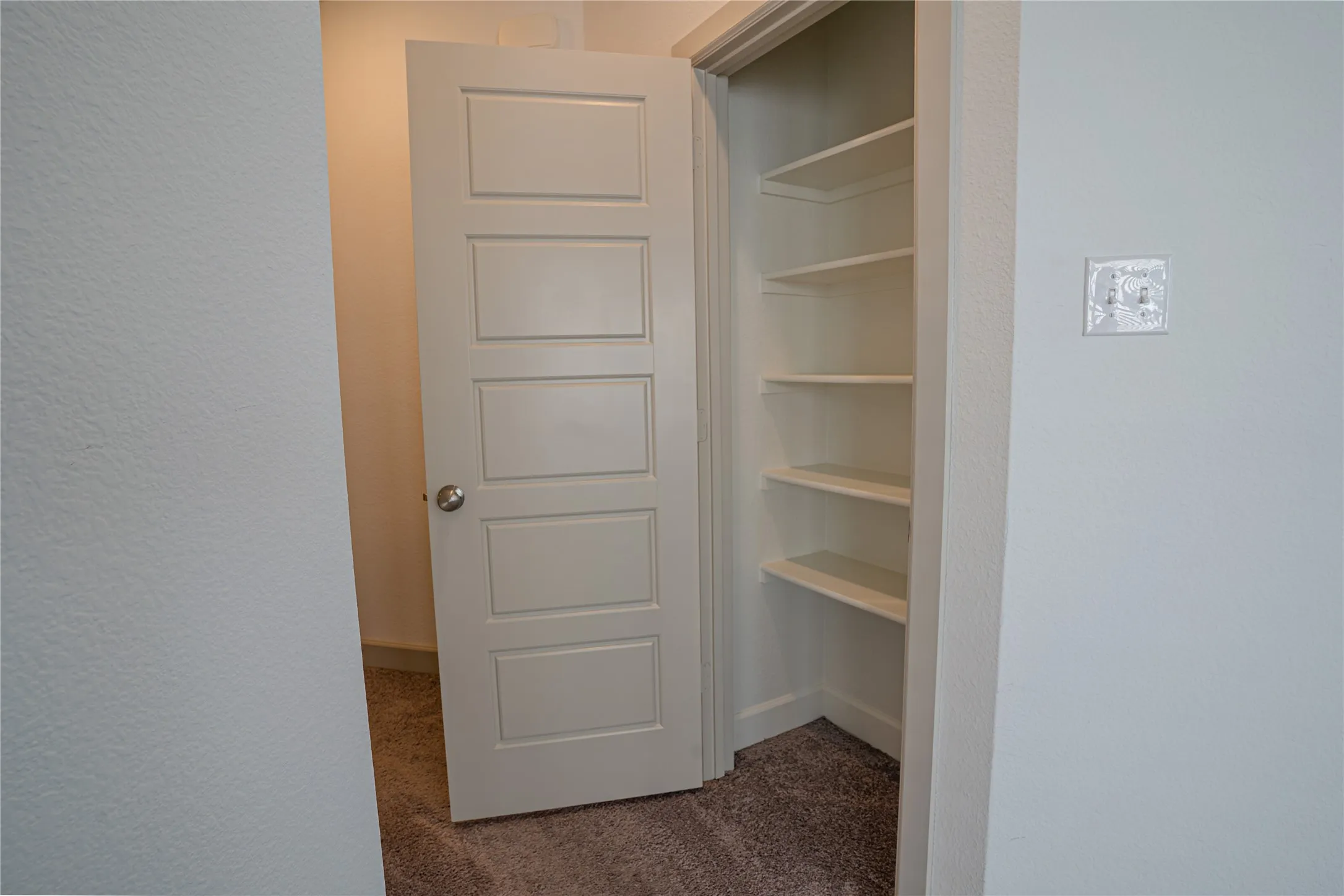Built-in shelving with multiple levels, paneled interior door, and textured wall finish