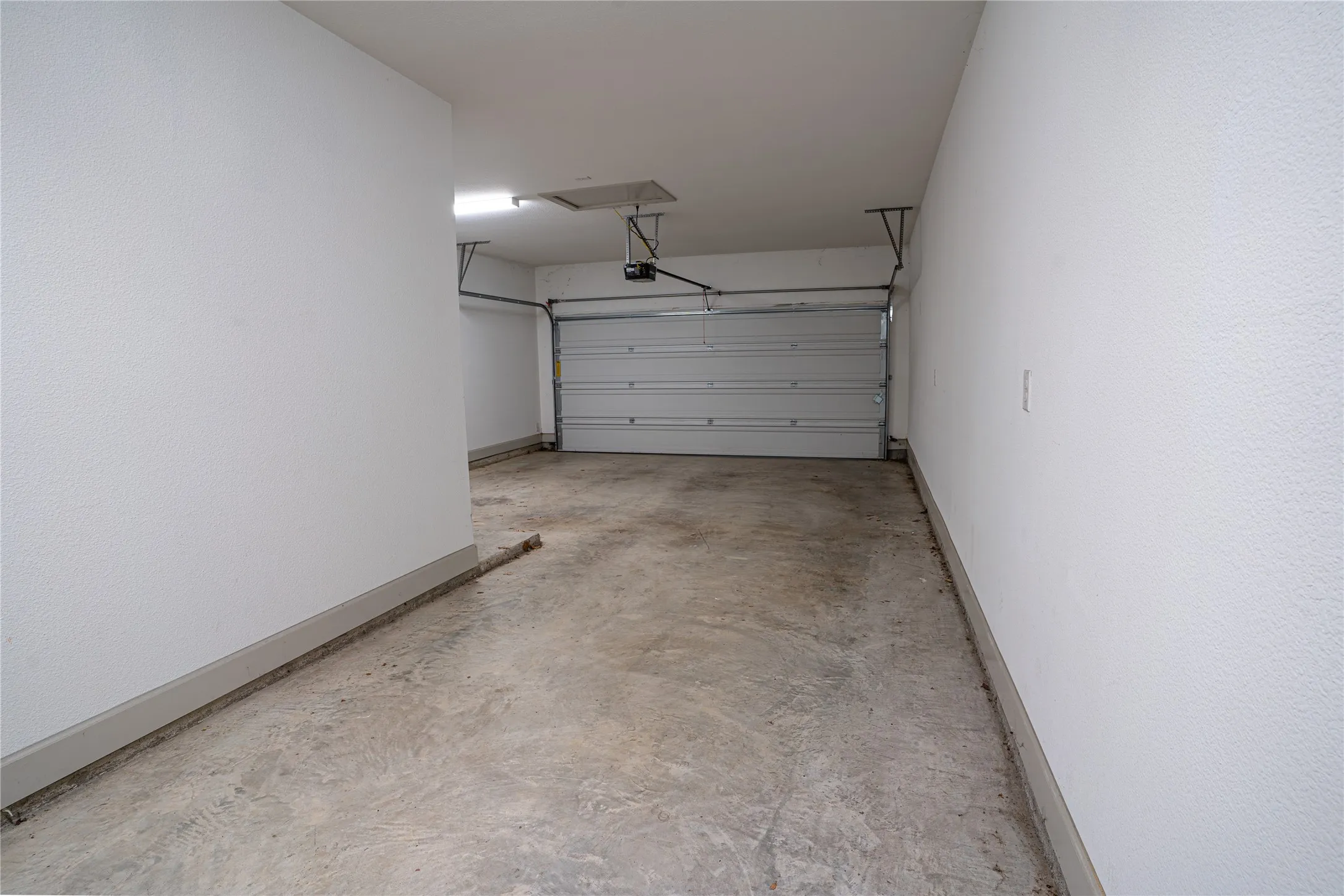 Attached garage with a roll-up door and concrete flooring