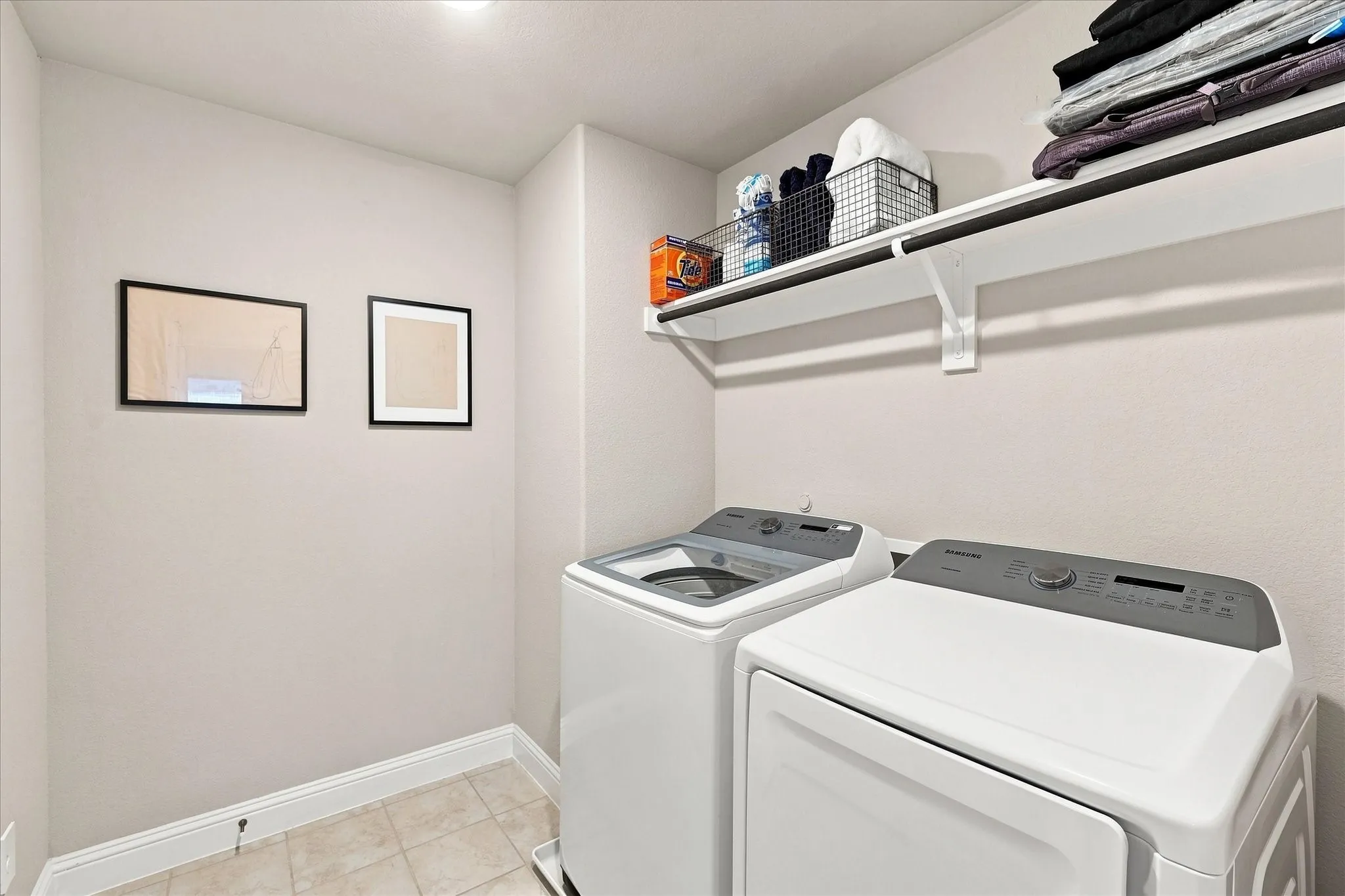 Dedicated laundry area featuring a white storage shelf, overhead lighting, and tile flooring