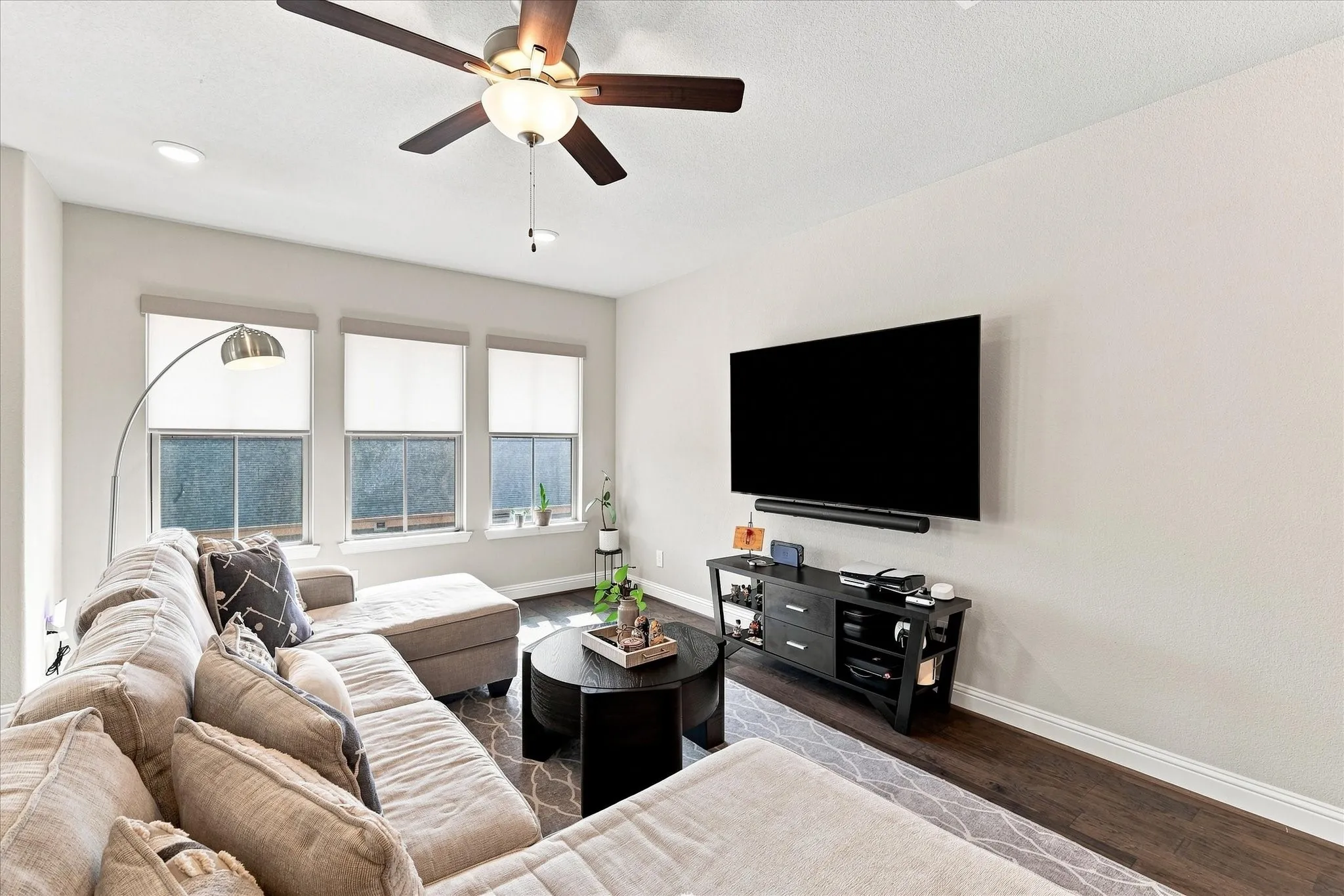 Hardwood-finish flooring, recessed lighting, ceiling fan with integrated light, multiple windows, and neutral wall tones