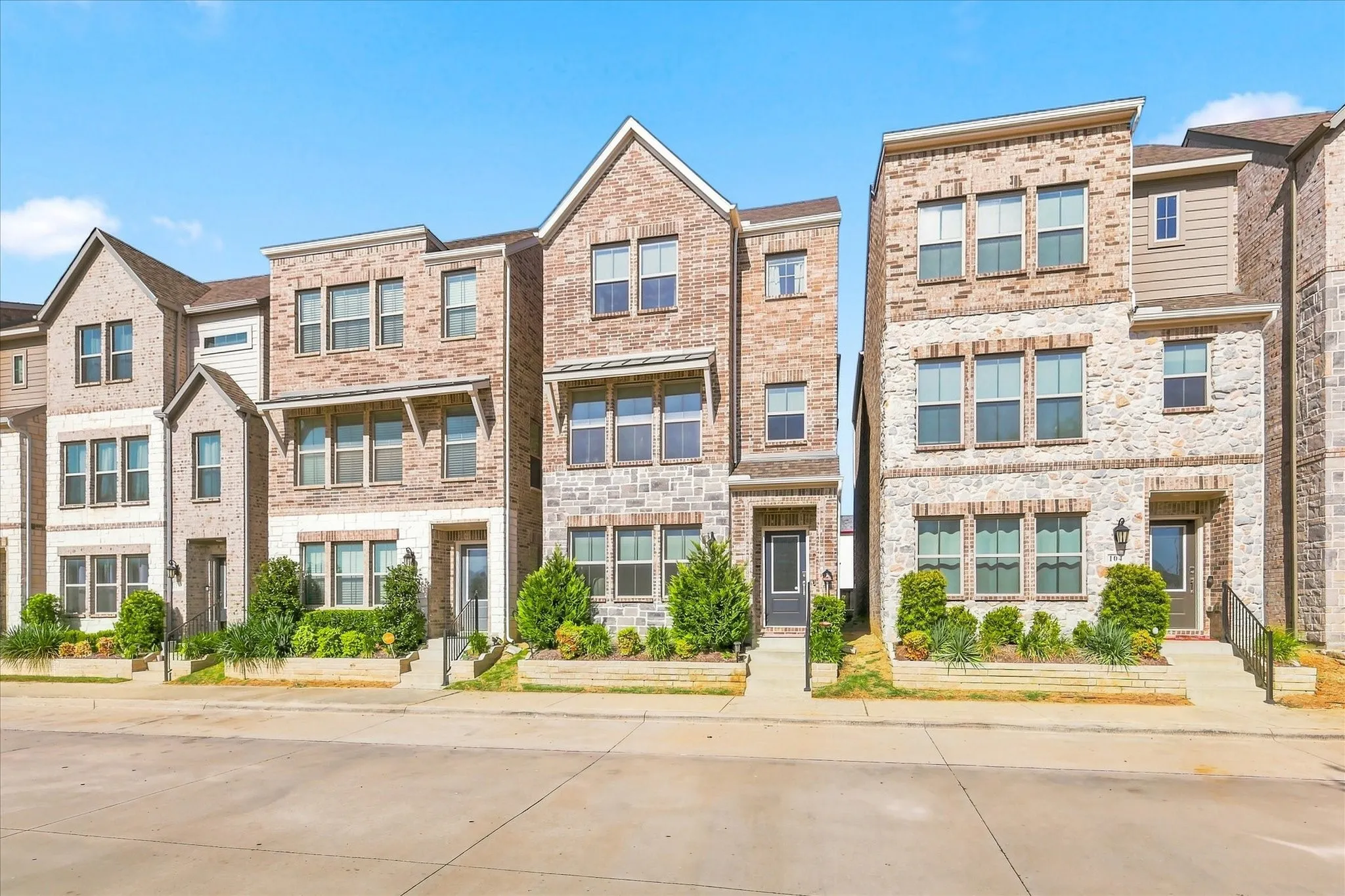 Modern detached featuring a brick and stone facade, multi-level construction, and architectural window awnings