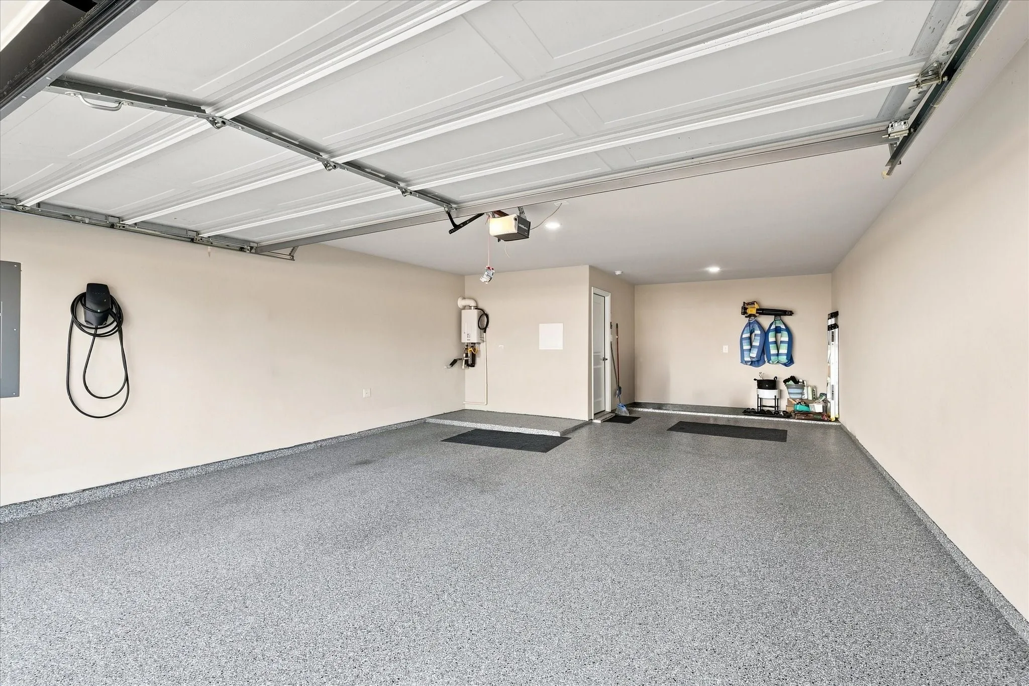 Spacious garage with speckled epoxy flooring and a TESLA charger painted walls, and an electric vehicle charging station