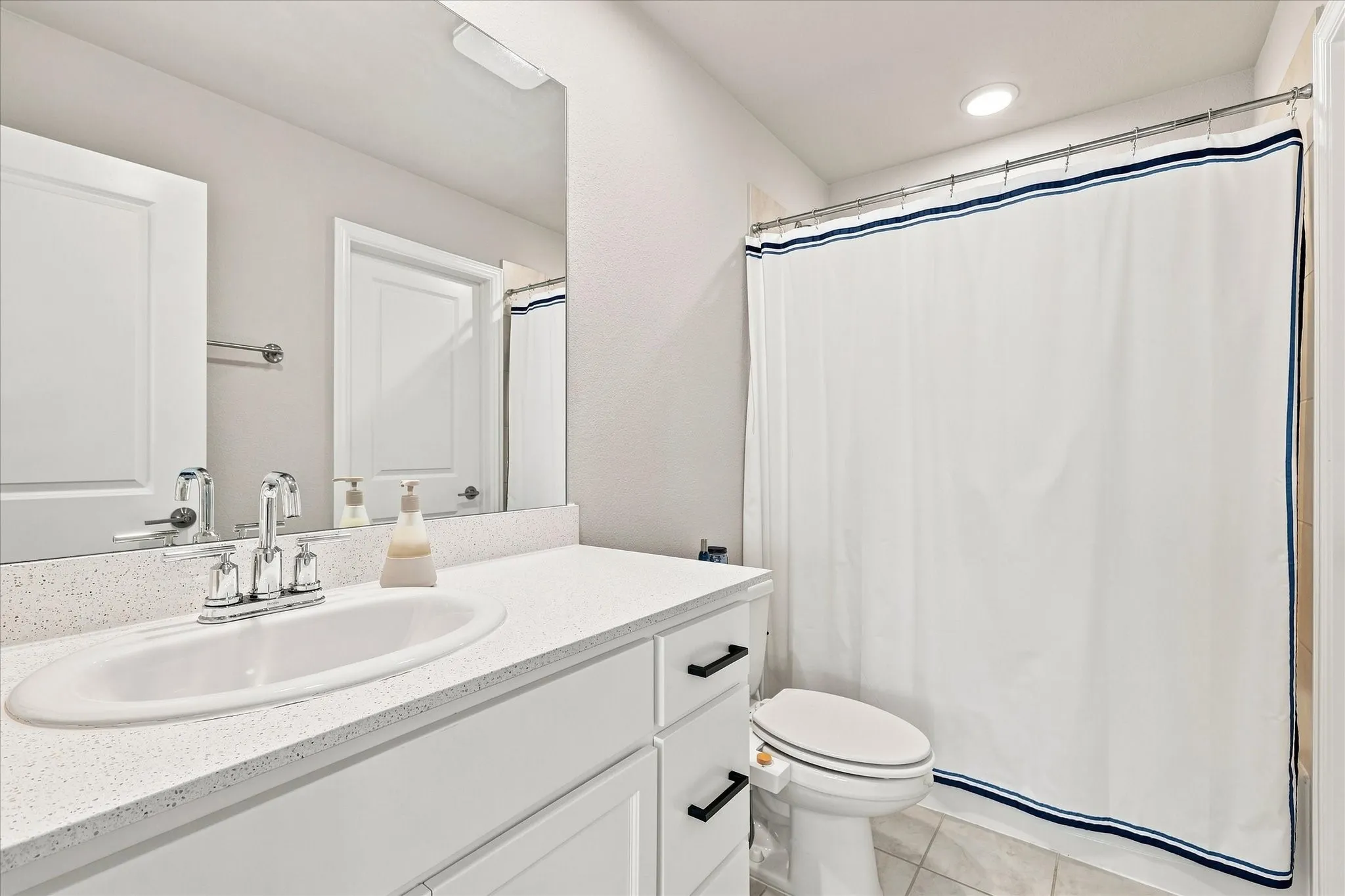 White vanity with black hardware, integrated sink, and speckled countertop